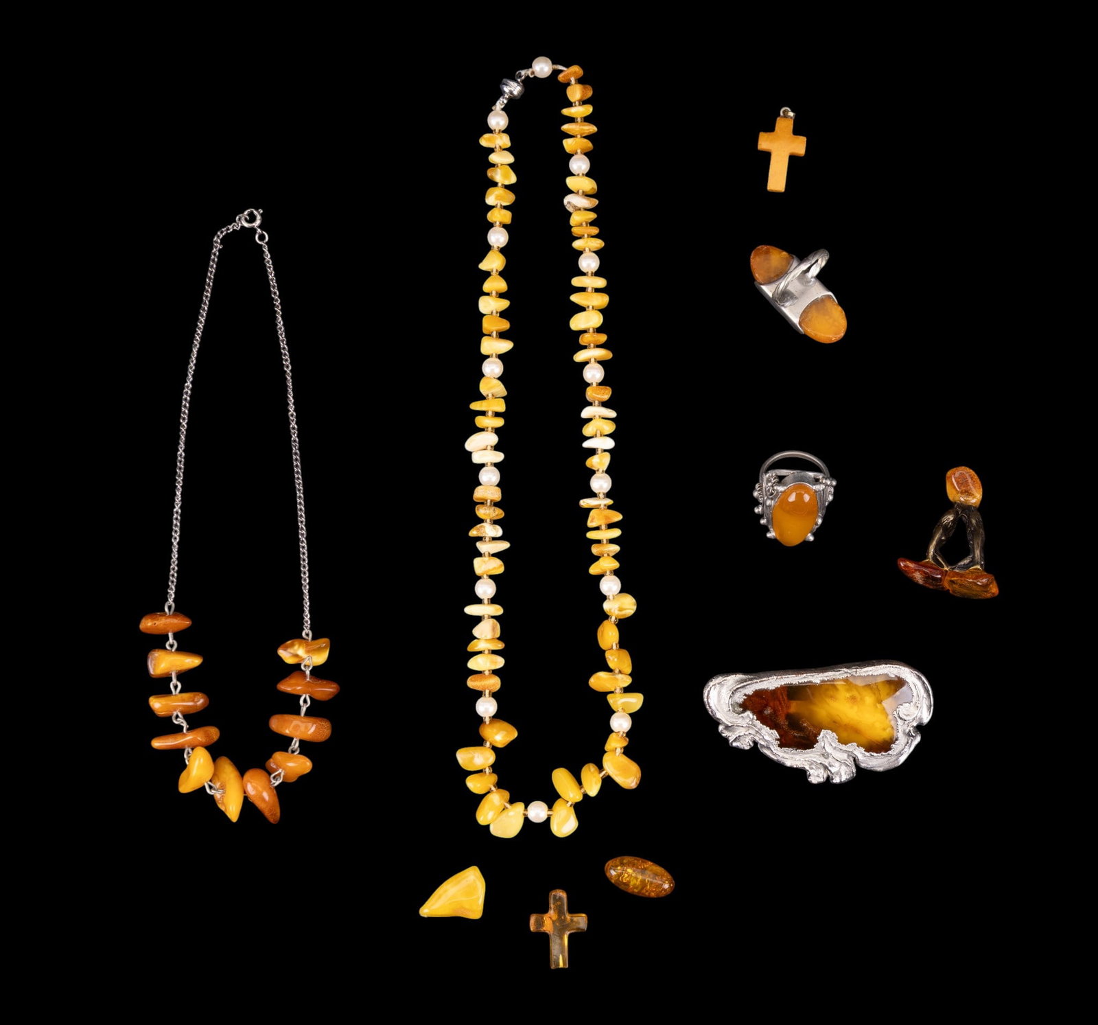 Vintage Amber Jewelry Group: A collection of vintage amber jewelry including an Art Nouveau brooch, charms, Crosses, rings, sizes 7 and 8, a smooth nugget collar necklace, and a smooth butterscotch and faux pearl necklace, measur