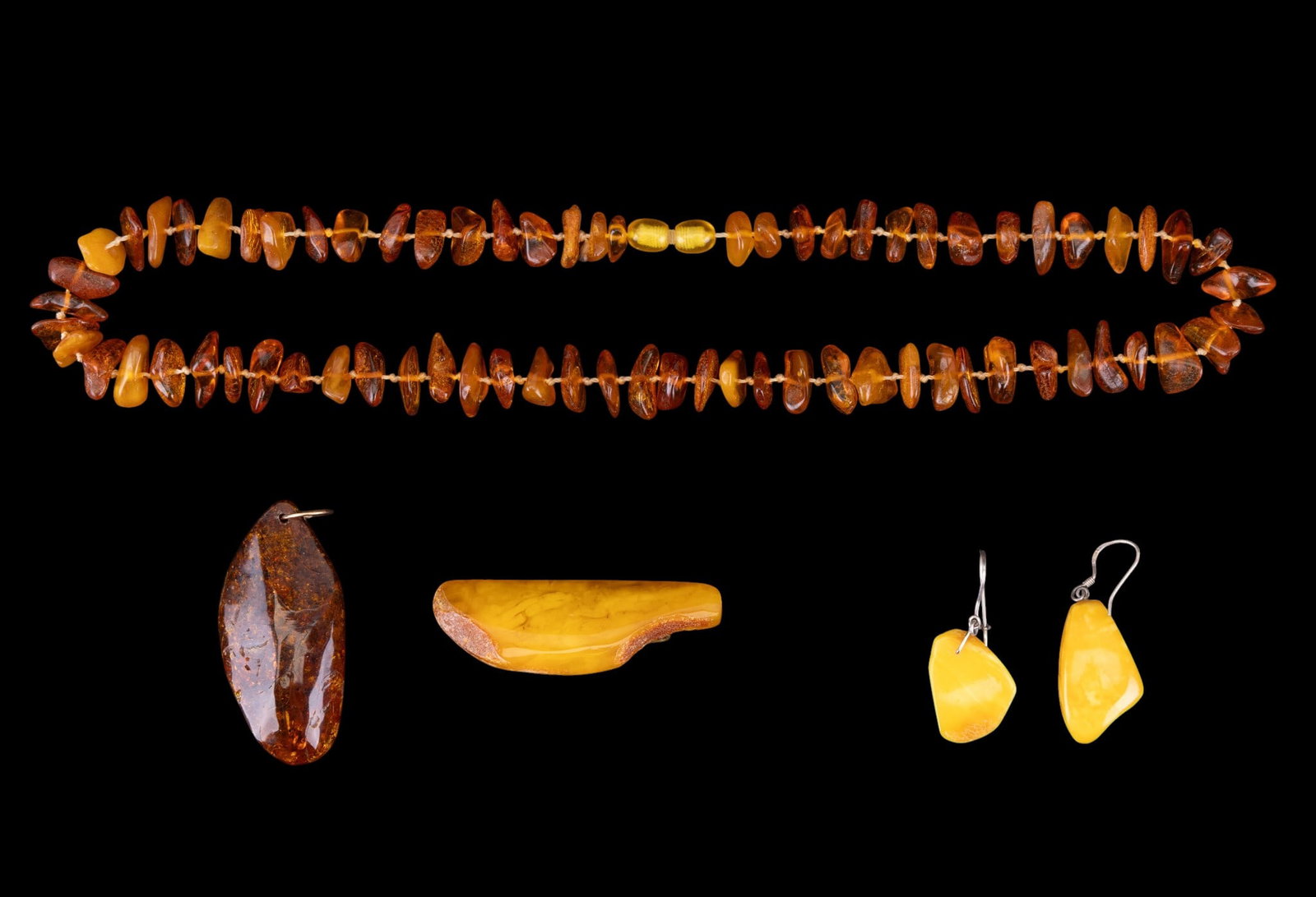 Early Amber Jewelry Group: A collection of early amber jewelry including a chunk necklace, measures approx. 10" on the drop, a natural amber smooth pendant, butterscotch dangle earrings, and a butterscotch bobby pin.