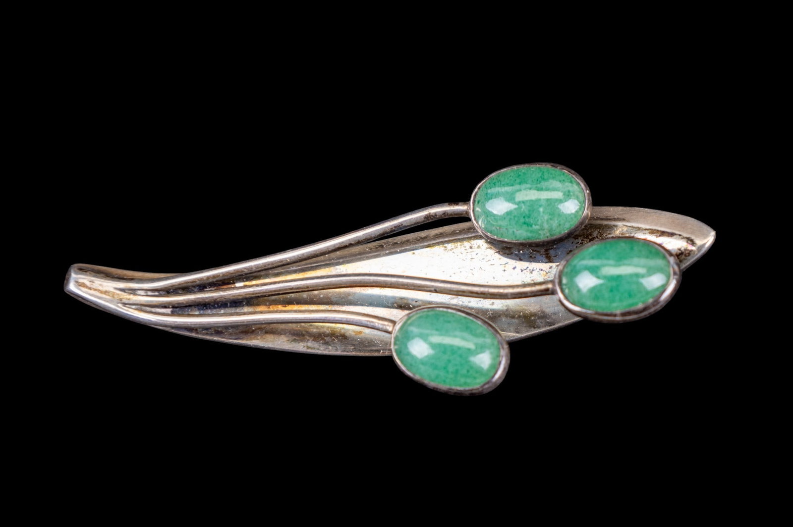 Sigi Tasco Signed Mexican Sterling Silver Brooch: A signed Sigi Tasco Mexican sterling silver figural brooch with three housed green polished stones. Item measures approx. 2.5" wide x 1" top to bottom.
