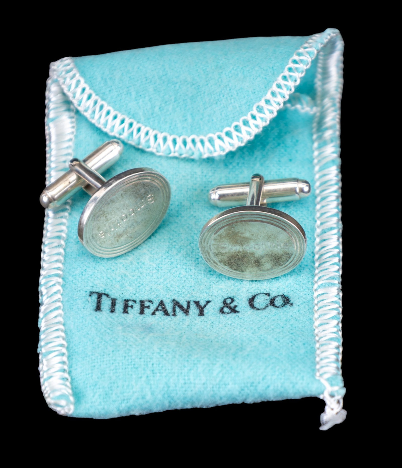 Tiffany & Co. Sterling Silver Cufflinks: A pair of Tiffany sterling silver monogrammed cufflinks marked Tiffany & Co. 925 on back, items read "smoothie" on front of cufflinks. Includes Tiffany carrying cloth bag and box.
