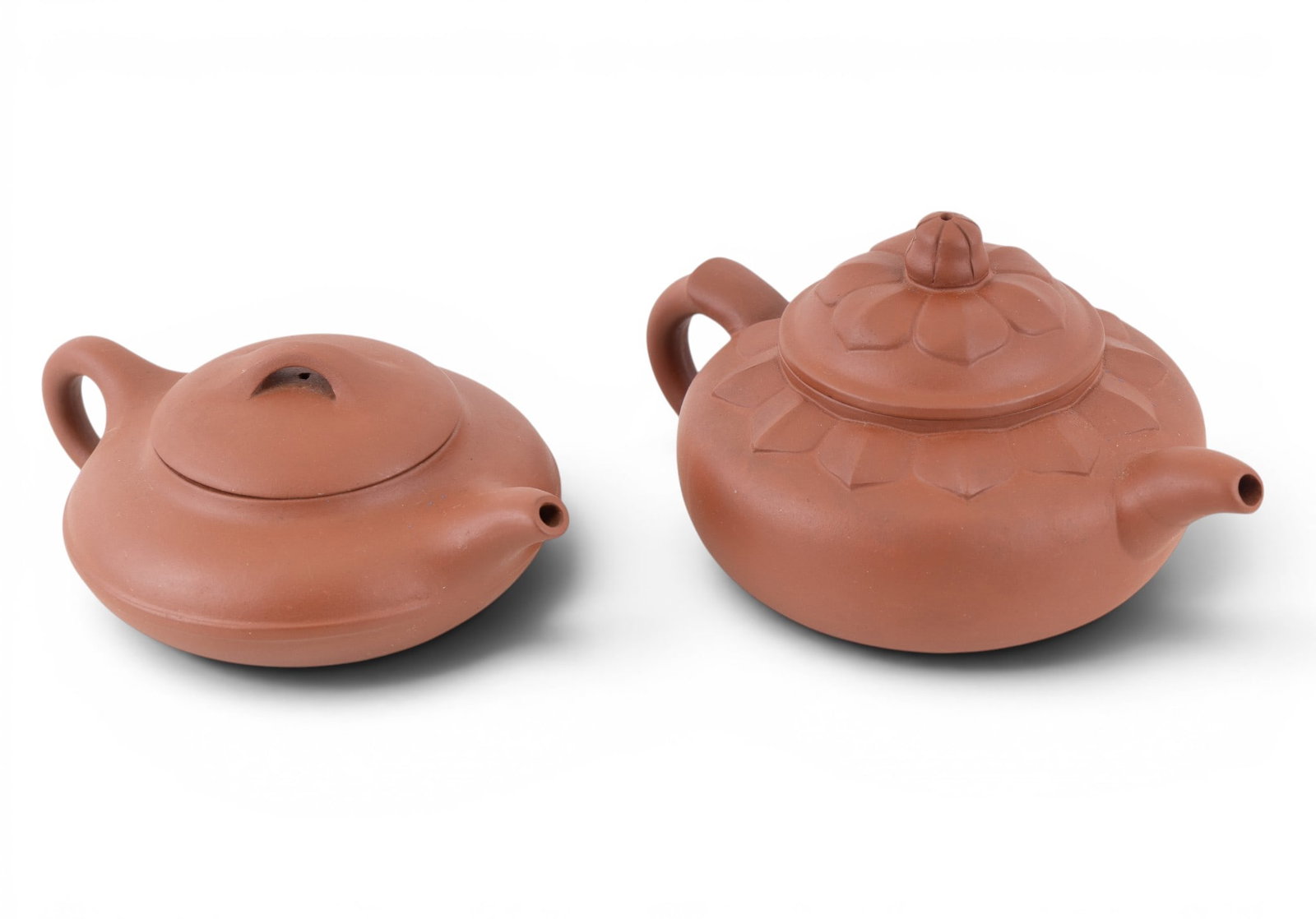 Chinese Yixing Zisha Clay Teapots (2): Two Chinese Yixing Zisha red clay teapots, one is squat in stature and smooth, the other is slightly taller, approx. 3.25" H, and features a lotus flower style raised design. Both teapots feature a fo
