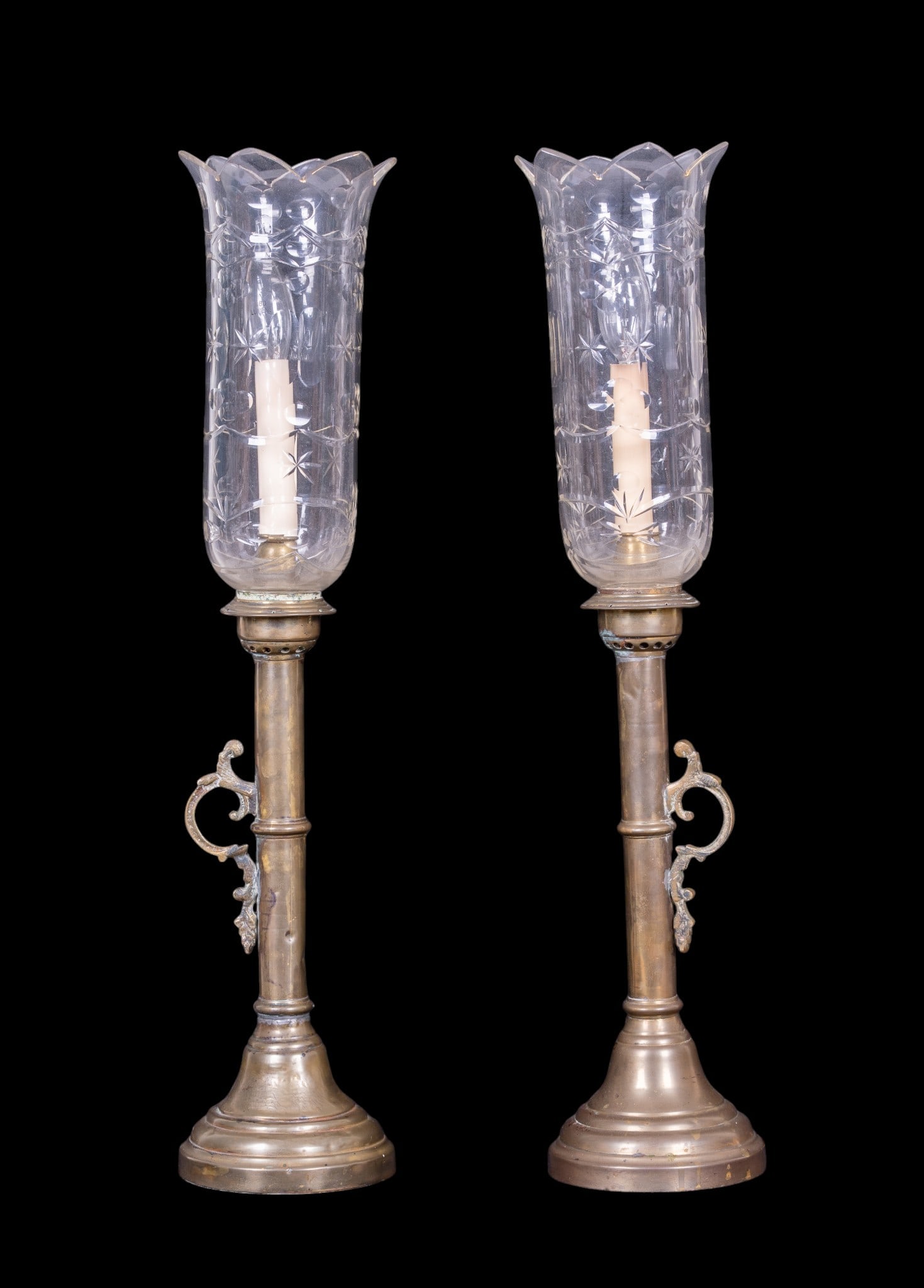 Vintage Brass Candlestick Lamps, Cut Glass Shades: A pair of vintage brass candlestick lamps featuring flared petal cut rimmed cut glass hurricane shades, untested, both measure approx. 23.5" H. Note some dents and restorations.