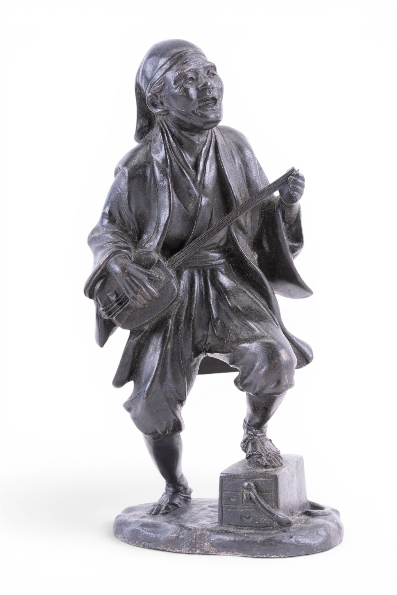 Japanese Bronze Figure of Street Musician: Antique bronze figural sculpture depicting a traveling musician playing a shamisen while standing atop a chest, impressed seal mark to base. Some loss to back and shamisen as seen in photos. Measures 