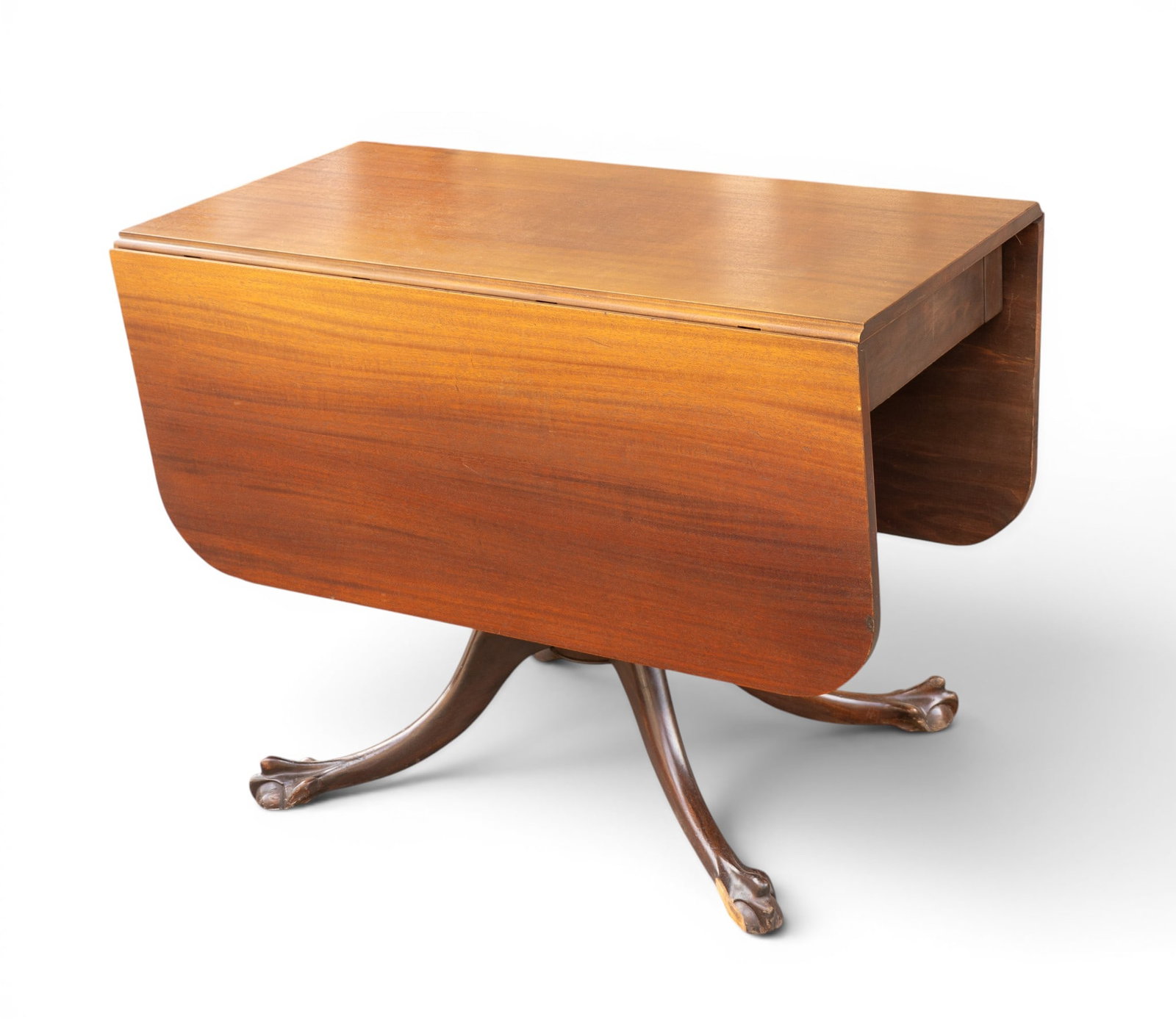 Mahogany Drop-Leaf Table with Claw Feet: Mahogany drop-leaf table featuring a rectangular top with hinged leaves that can be raised for additional surface area. Supported by a central turned pedestal terminating in four carved claw feet. Inc