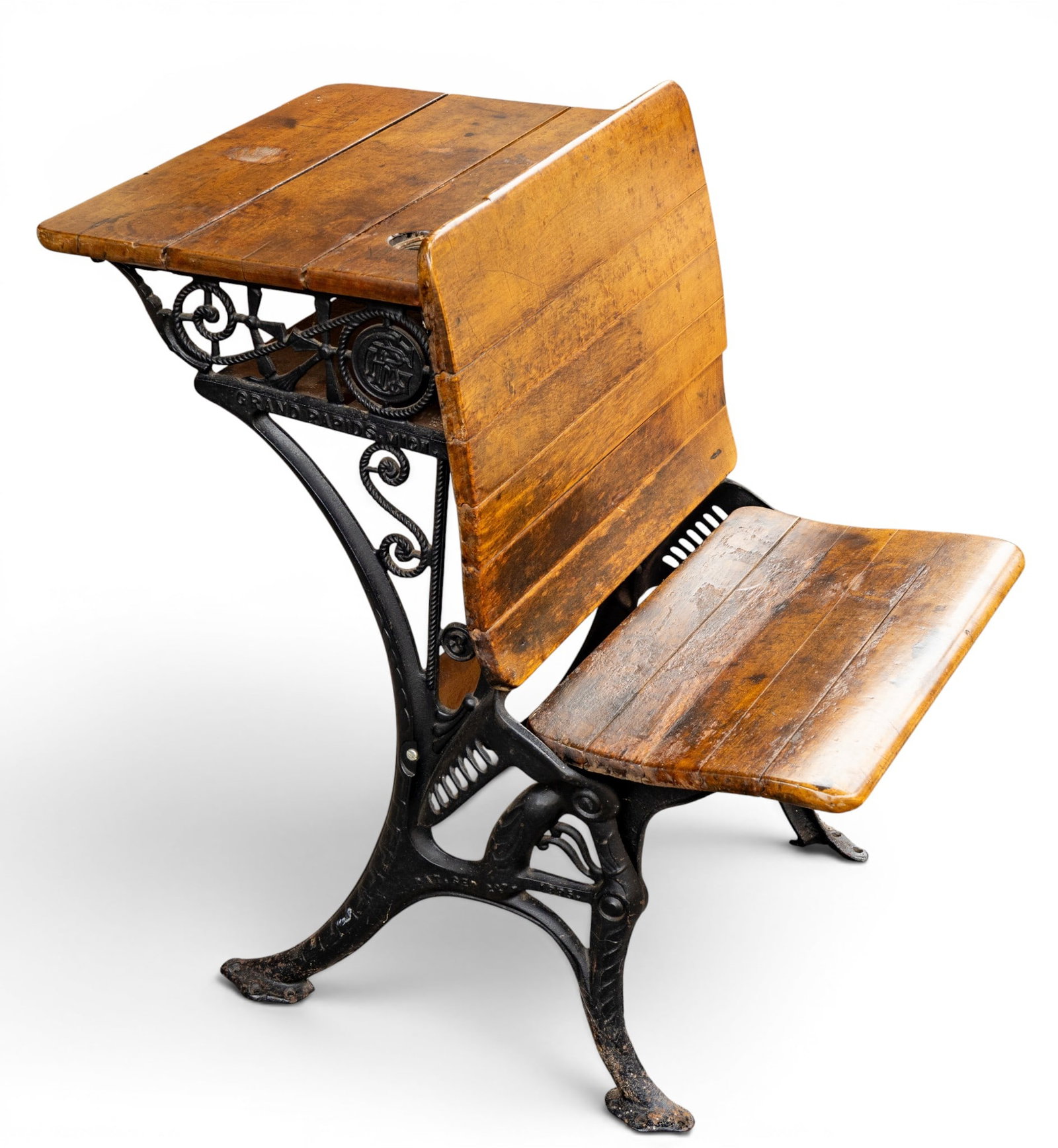 School Desk / Seat on Ornate Cast Iron Base: Antique-style school desk marked from Grand Rapids, Michigan. Features a wood desktop and seat with visible grain, supported by an ornate cast iron base. Measures approximately 21 in wide x 22 in