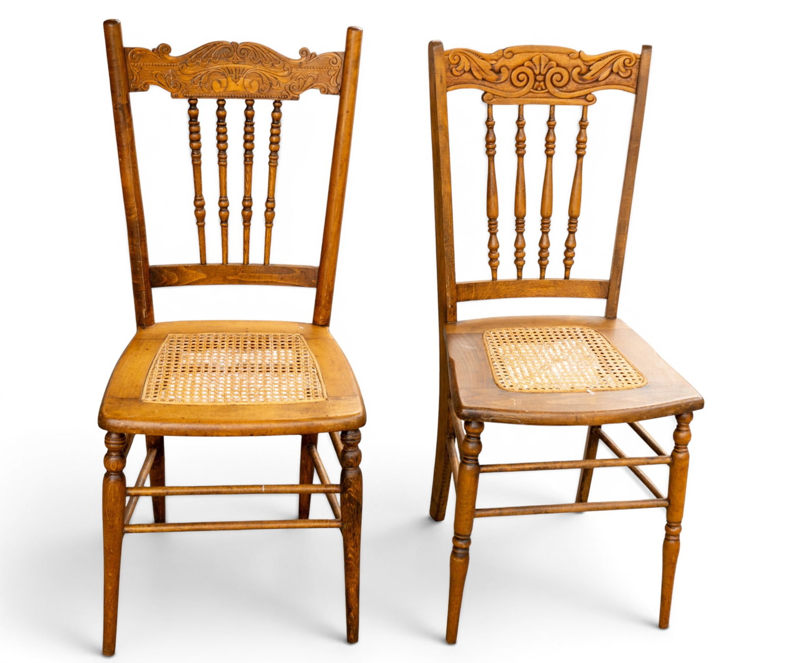 Cane Seat Spindle Back Chairs: Wooden side chairs featuring caned seats and decorative carved backrests. The spindled design on the backrest is complemented by intricate carved details. Chairs measure approximately 16.5 inches