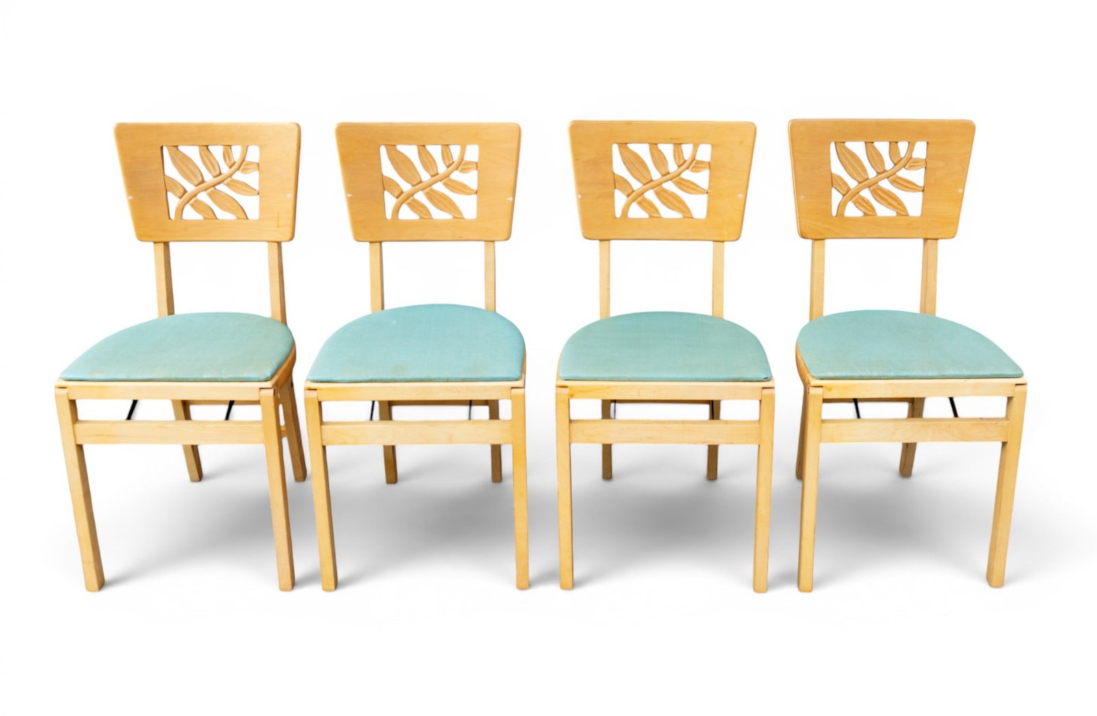 Mid Century Stakmore Furniture Folding Chairs: A set of four mid century folding chairs featuring a carved leaf design in the backs and green textured vinyl upholstery by Stakmore Furniture Co. All chairs measure approx. 16" W x 17" D x 32" H. Not