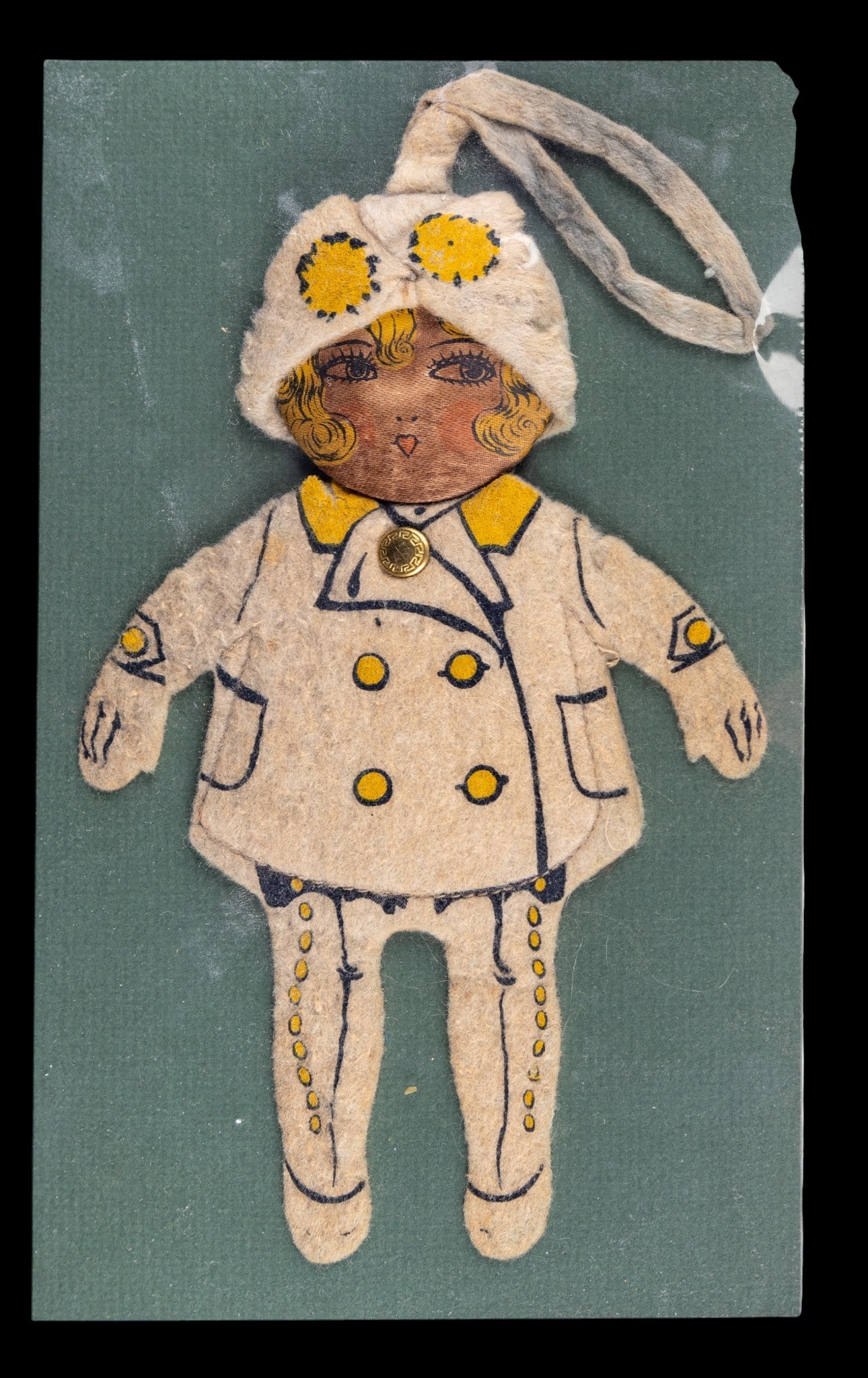 Danahy-Faxon Promotional Felt Doll: Vintage felt doll featuring stitched details and a detachable hat, produced as a promotional item for Danahy-Faxon Home Owned Stores. The doll is enclosed in protective plastic and mounted against a b