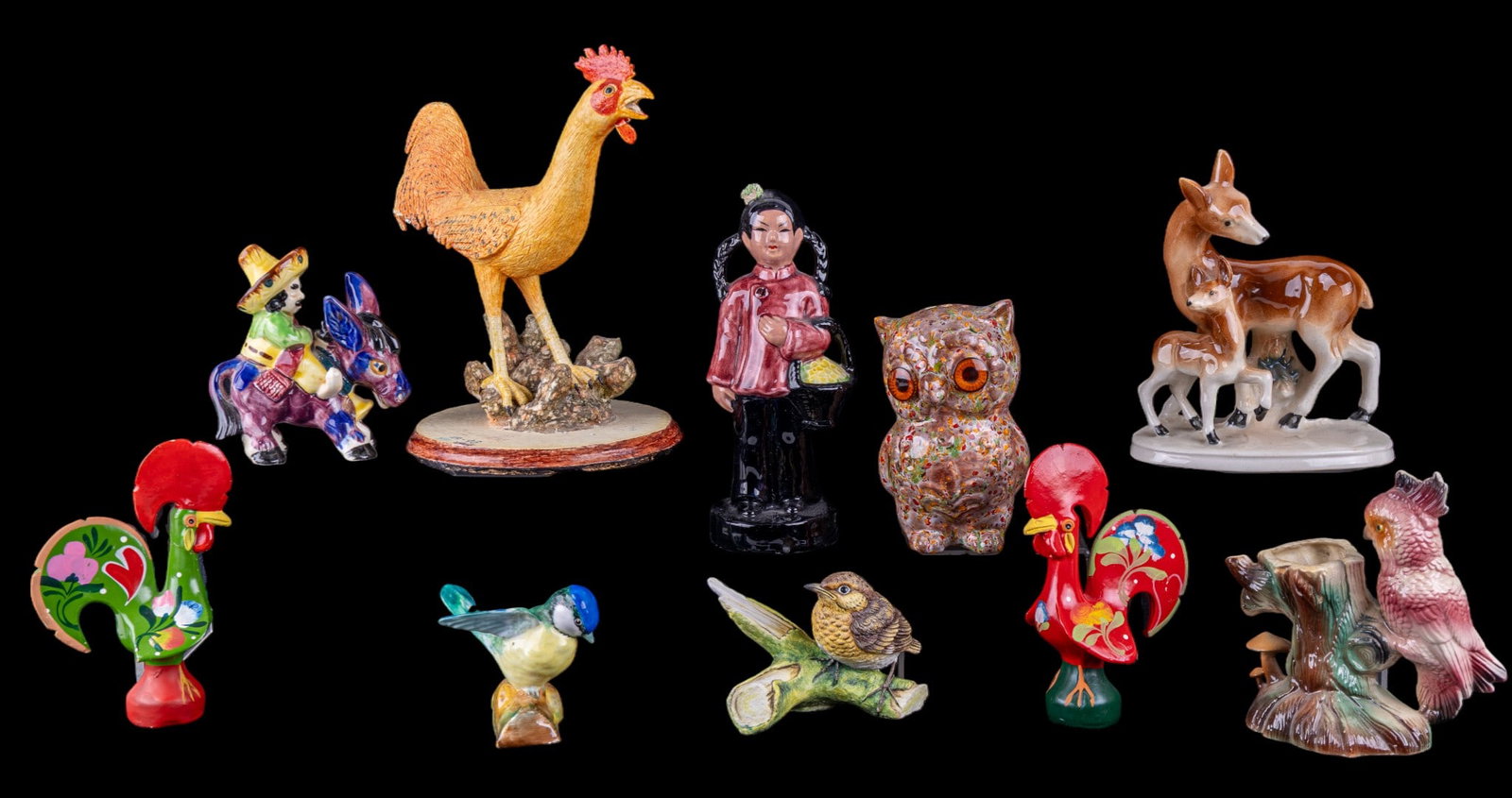 Mid Century Porcelain and Other Figurines: A collection of mid century figurines including a pair of hand painted Portuguese lucky chicken ceramic figurines, a man on a donkey, a doe and fawn statuette, a parrot vase, a hand painted papier mac