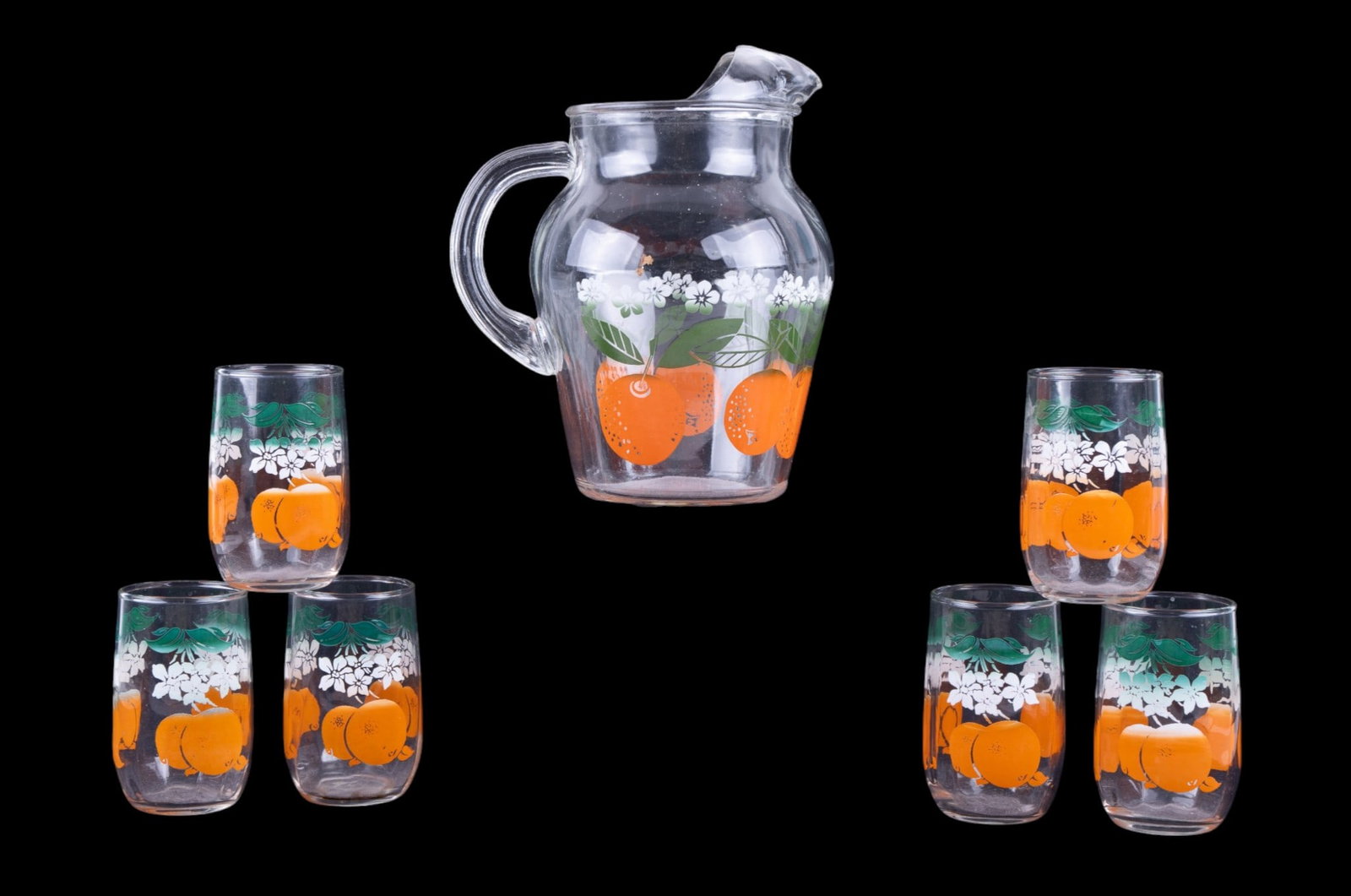 MCM Anchor Hocking Orange Juice Pitcher & Glasses: A mid century modern Anchor Hocking glass pitcher and six juice glass set featuring a stamped gradient orange fruit and blossom design. Pitcher measures approx. 7.5" H.