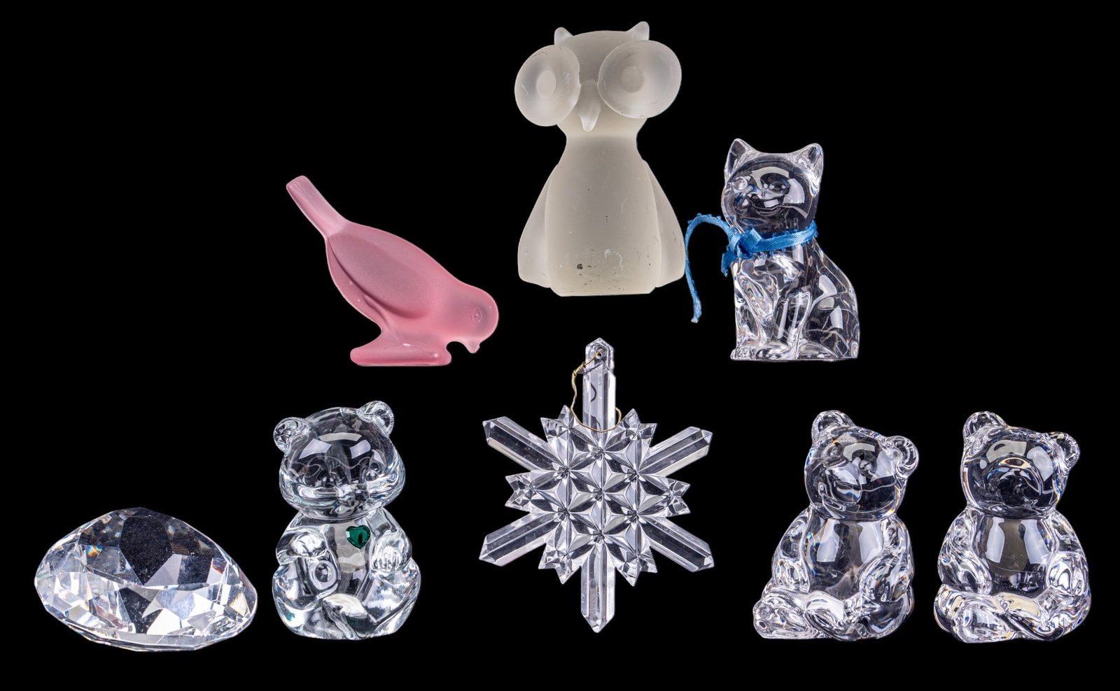 Crystal and Glass Animal Figurines: A collection of crystal and glass animal figurines featuring a pink frosted glass bird, a Fenton May birthstone glass bear, an unmarked heart cut crystal paperweight, a Waterford crystal snowflake