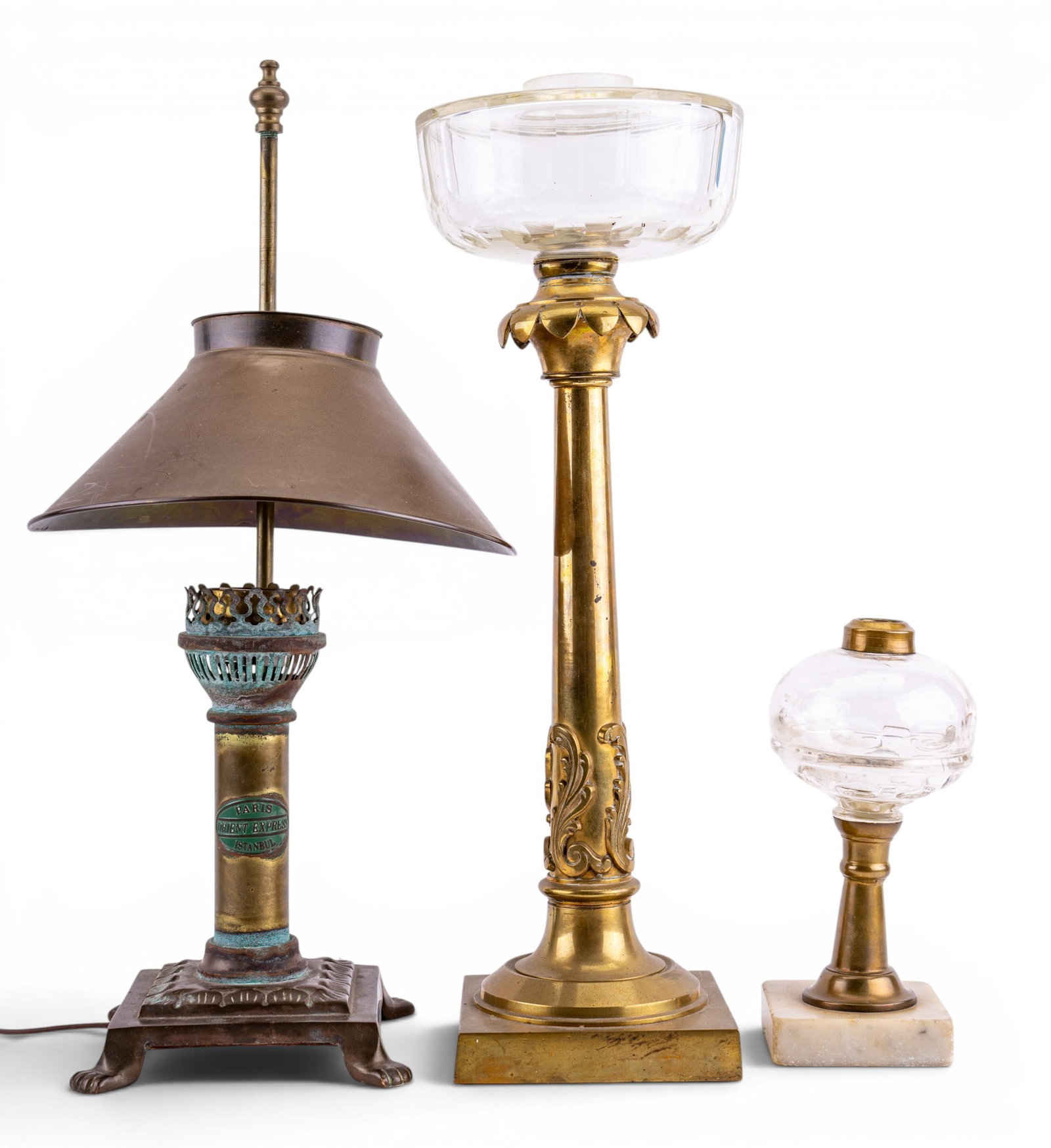 Early Brass Oil and Electric Lamps: A brass and glass 19th C oil lamp with cut glass chamber and scroll detail around the base of the pedestal, a small brass oil lamp with marble base and glass chamber, and a Paris Orient Express brass 