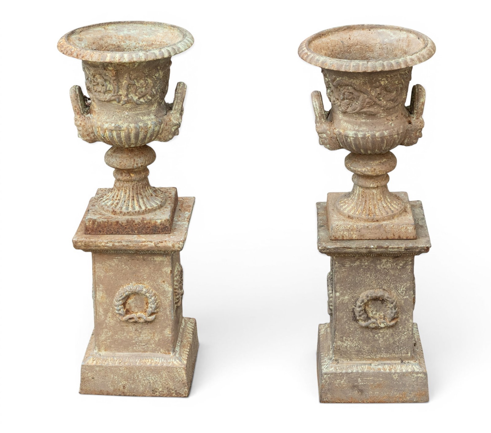 Pair of Cast Iron Urns on Bases: Pair of cast iron urns with flared rims, twin handles, and applied wreath decoration to bases. Urn and base are separate pieces. Assembled approx. 27.5" H x 10.5" Diameter.