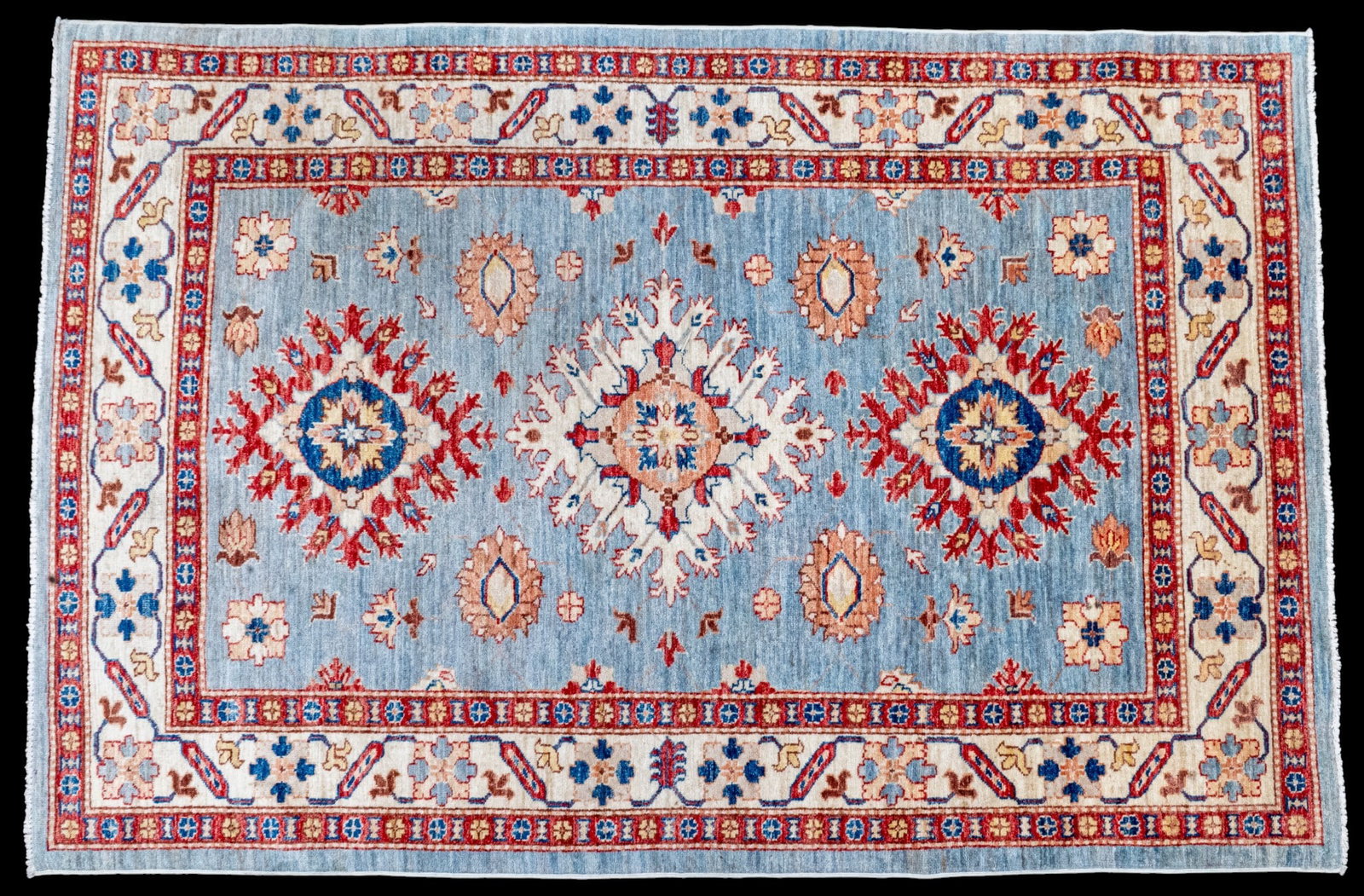 Kazak Rug w/ Light Blue Field ~ 4.5' x 6.75': Kazak hand-knotted wool carpet featuring a blue background with red and beige details. Measures approx. 4'7" x 6'9".