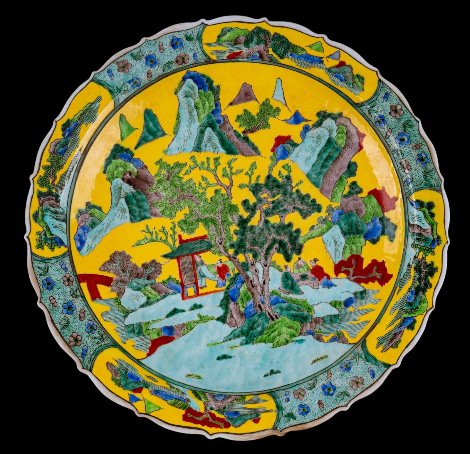Large Chinese Famille Jaune Charger: Large 20th century Chinese hand painted famille jaune porcelain charger decorated with an extensive mountainous landscape featuring scholars, pavilions, and flowering trees against a yellow ground. Sc