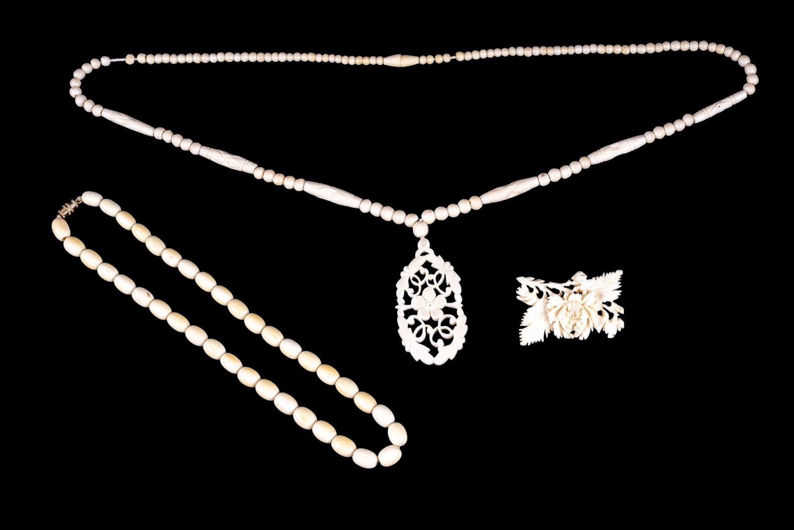 Vintage Carved Bone Jewelry: An intricate carved brooch, a bead necklace, and one with a floral carved pendant.