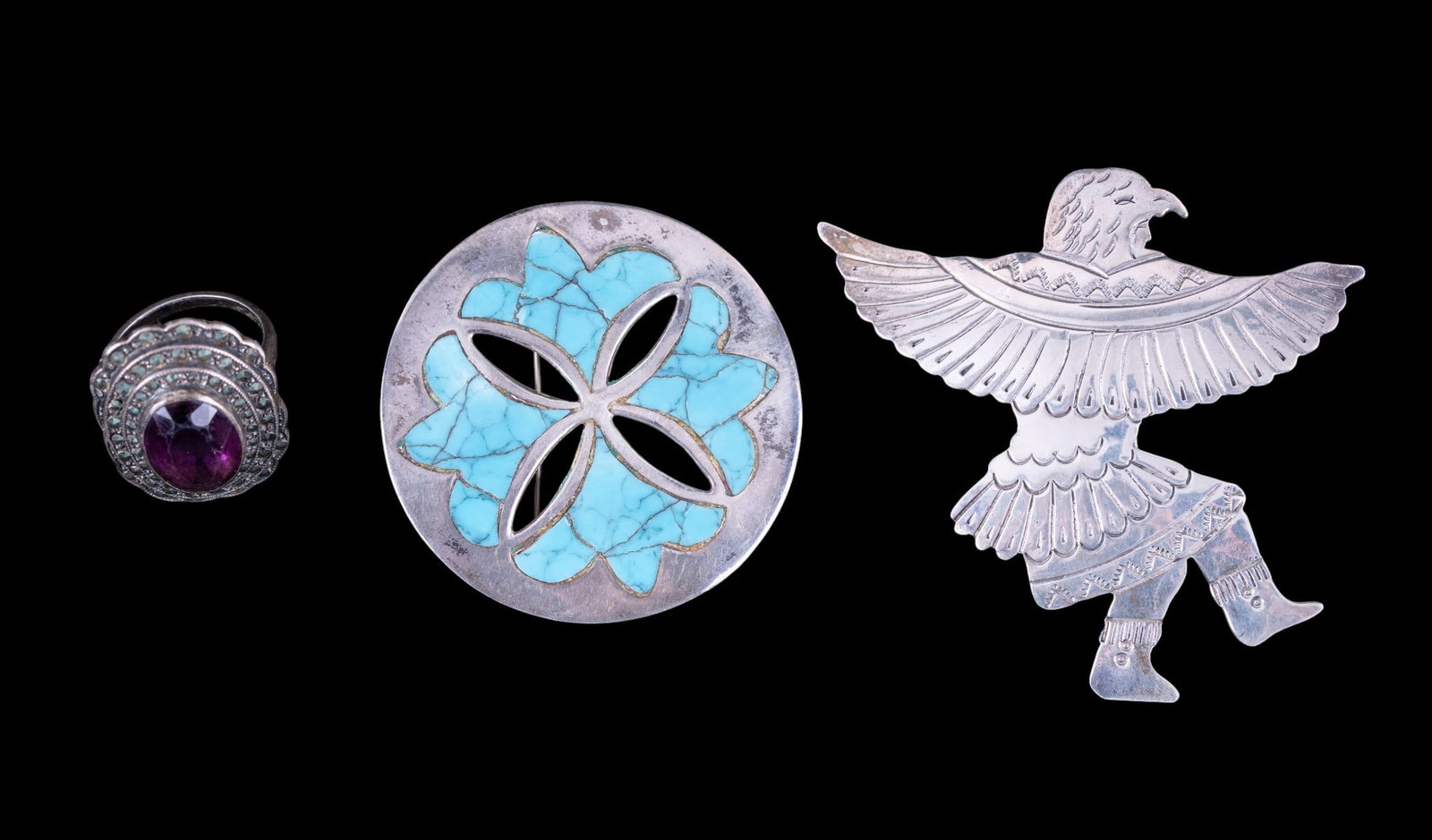 Taxco and Navajo Sterling Jewelry: A Taxco sterling brooch with turquoise inlay, an etched sterling Eagle Dancer brooch signed 'RW" for Navajo artist Ronnie Willie. and a sterling cocktail right with cut amethyst center wreathed in thr