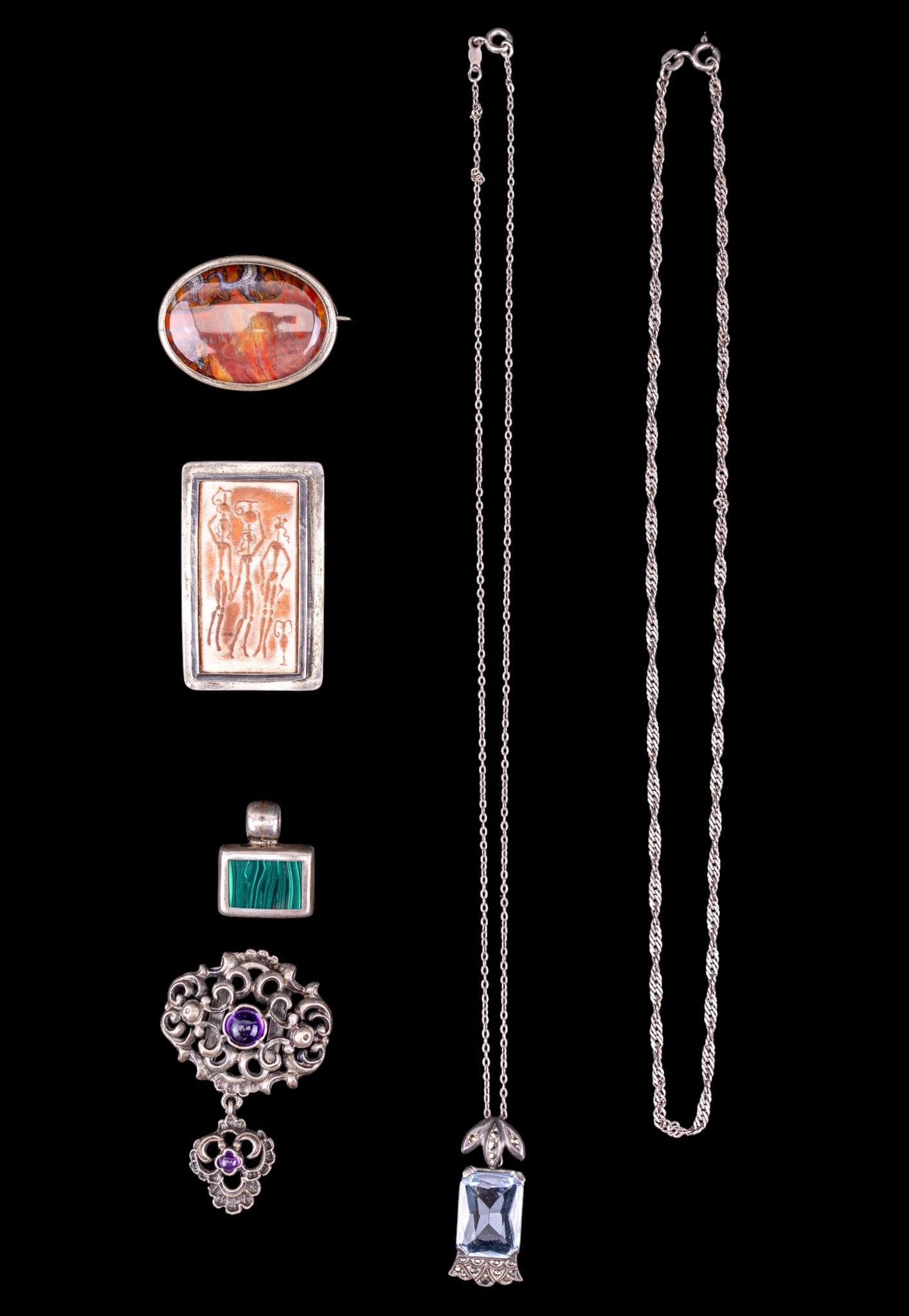 Early Sterling Silver Jewelry: A collection of sterling silver jewelry including a terra cotta relief tile brooch, a malachite pendant, an ornate pendant with amethyst cabochons, a red jasper polished oval brooch, a blue topaz/aqua