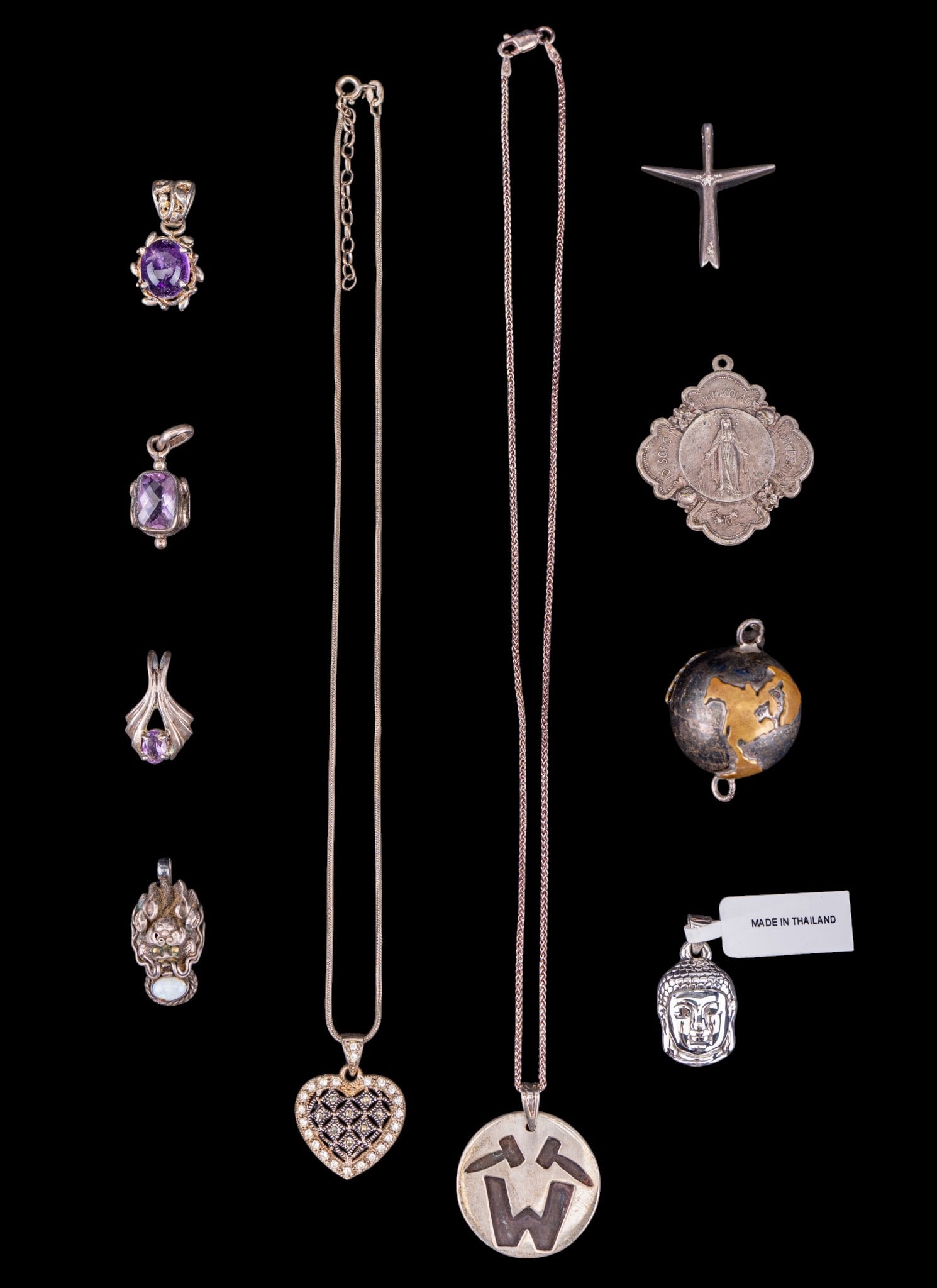 Sterling and Silver Pendants: A collection of pendants featuring sterling silver dragons head, Cross, cushion cut amethyst, oval cut amethyst, unmarked amethyst cabochon, marcasite heart and chain, embossed circular pendant and ch