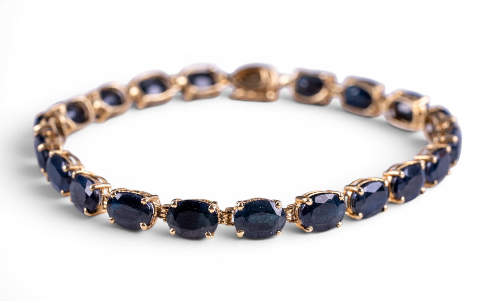 14K Gold and Sapphire Tennis Bracelet: A fine 14K yellow gold tennis bracelet featuring 20 oval cut dark blue Sapphires, measures approx. 7.25" end to end, and total weight is approx. 0.25oz.