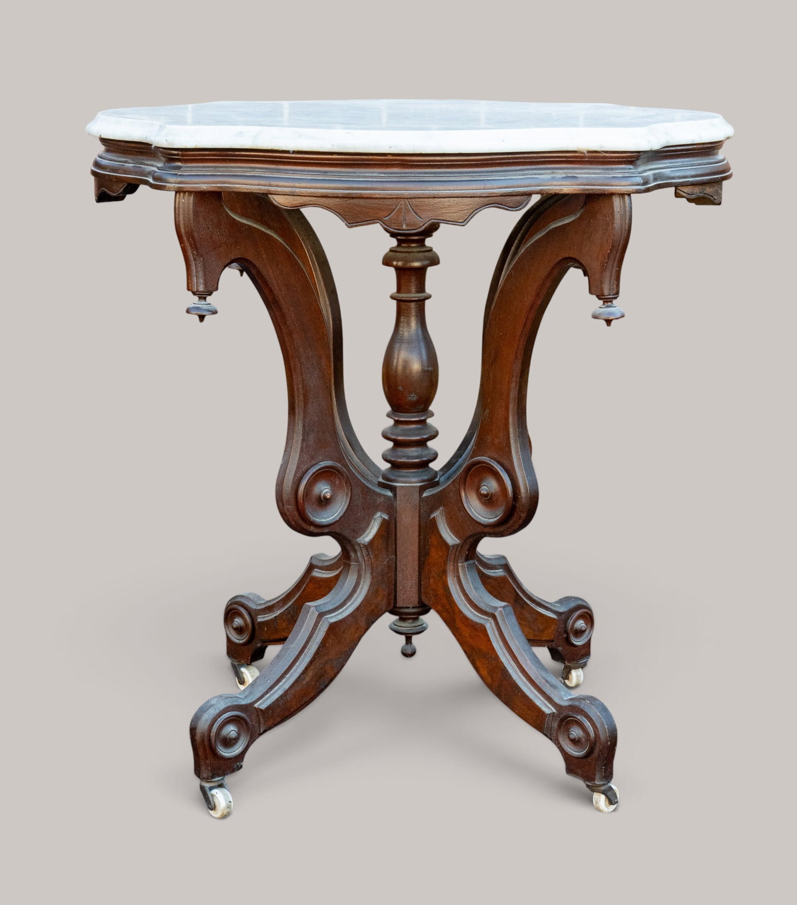 Victorian Marble Top Parlor Table: Victorian walnut parlor table featuring a shaped marble top. Base on castor wheels. Measures approx. 30" H x 28.5" W x 22" D.