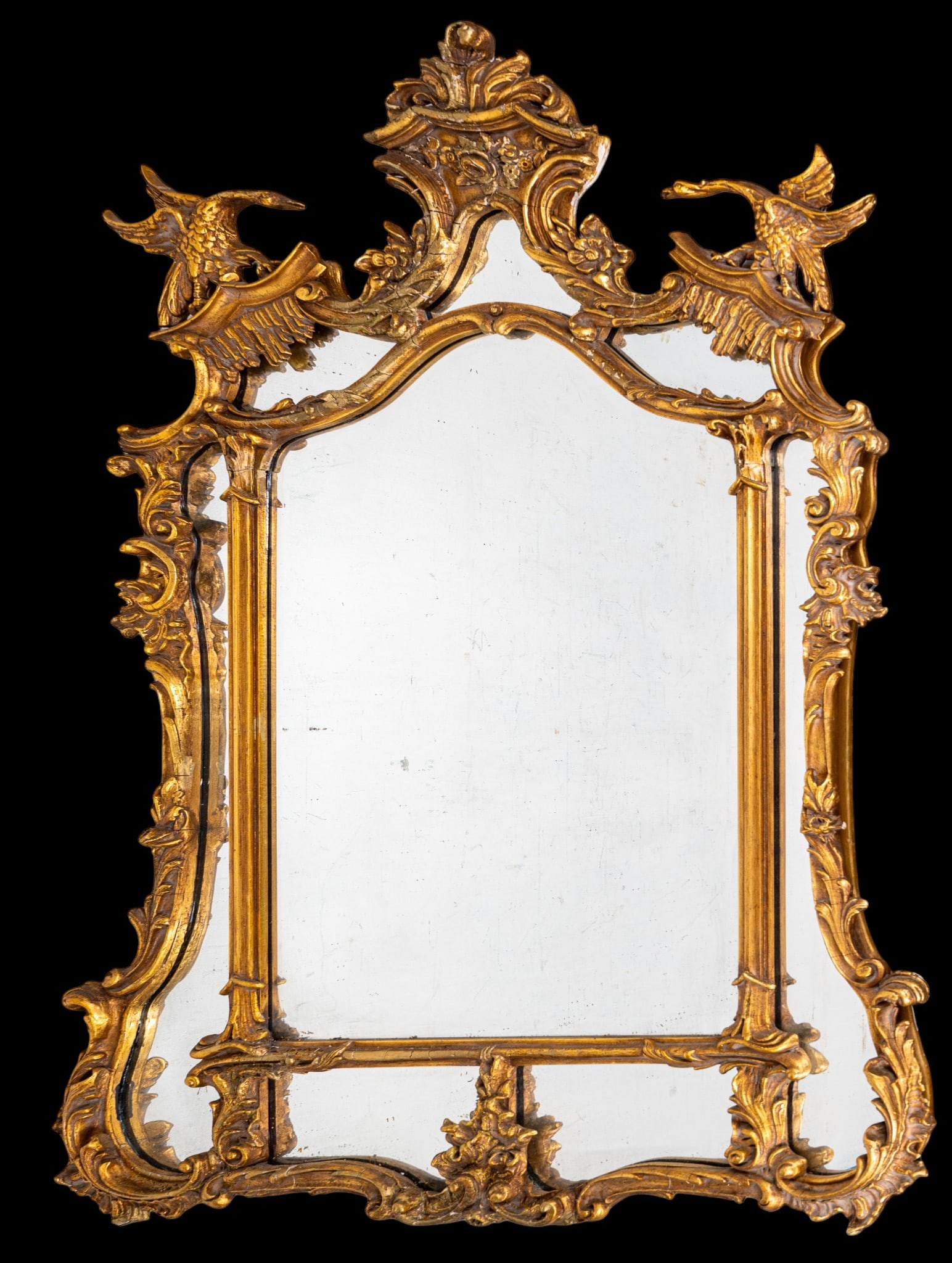 Antique Carved and Gilded Phoenix Mirror: Antique carved gesso wood wall mirror with gilt finish, featuring a Rococo-inspired crest with scrolling leaves, floral motifs, and a pair of opposing phoenixes flanking upper section. Beveled mirror.