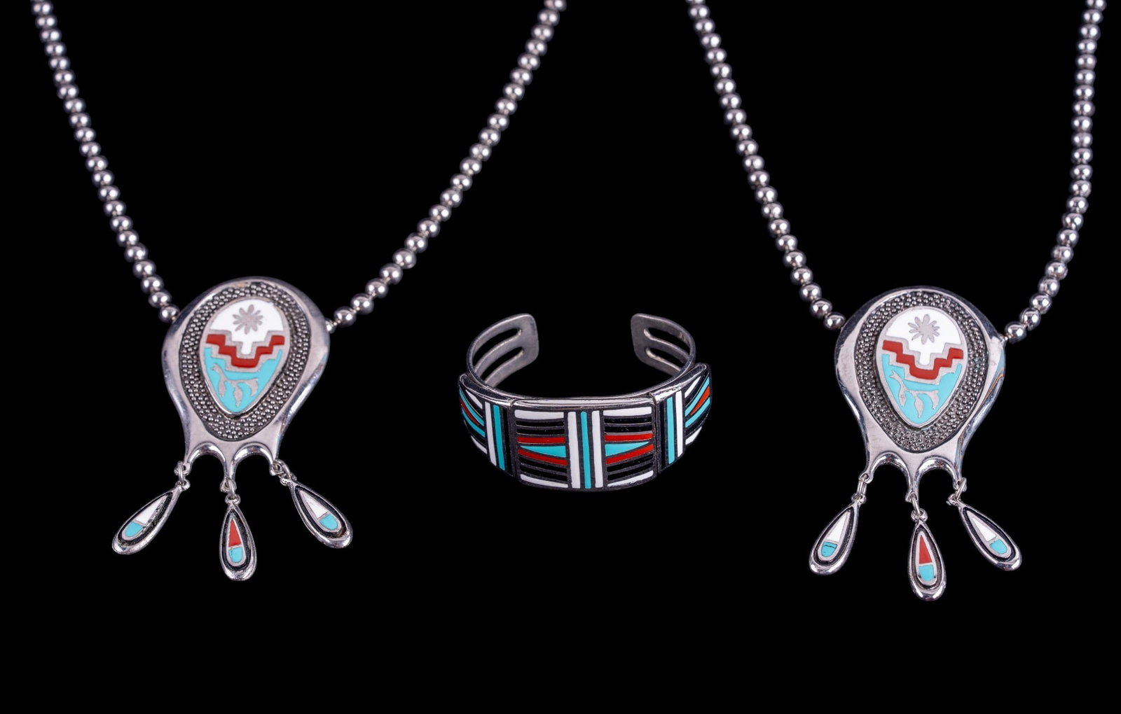 Southwest Style Jewelry: A pair of silver tone squash blossom style necklaces and a wide cuff bracelet.