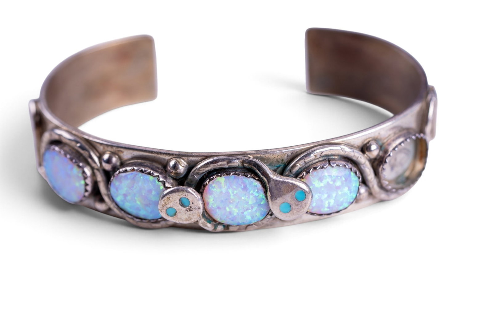Opal Zuni Snake Bracelet: Native American Zuni silver cuff bracelet signed by maker, set with 4 large opals and decorated with a pair of snakes with turquoise eyes. 1 opal missing from bracelet.