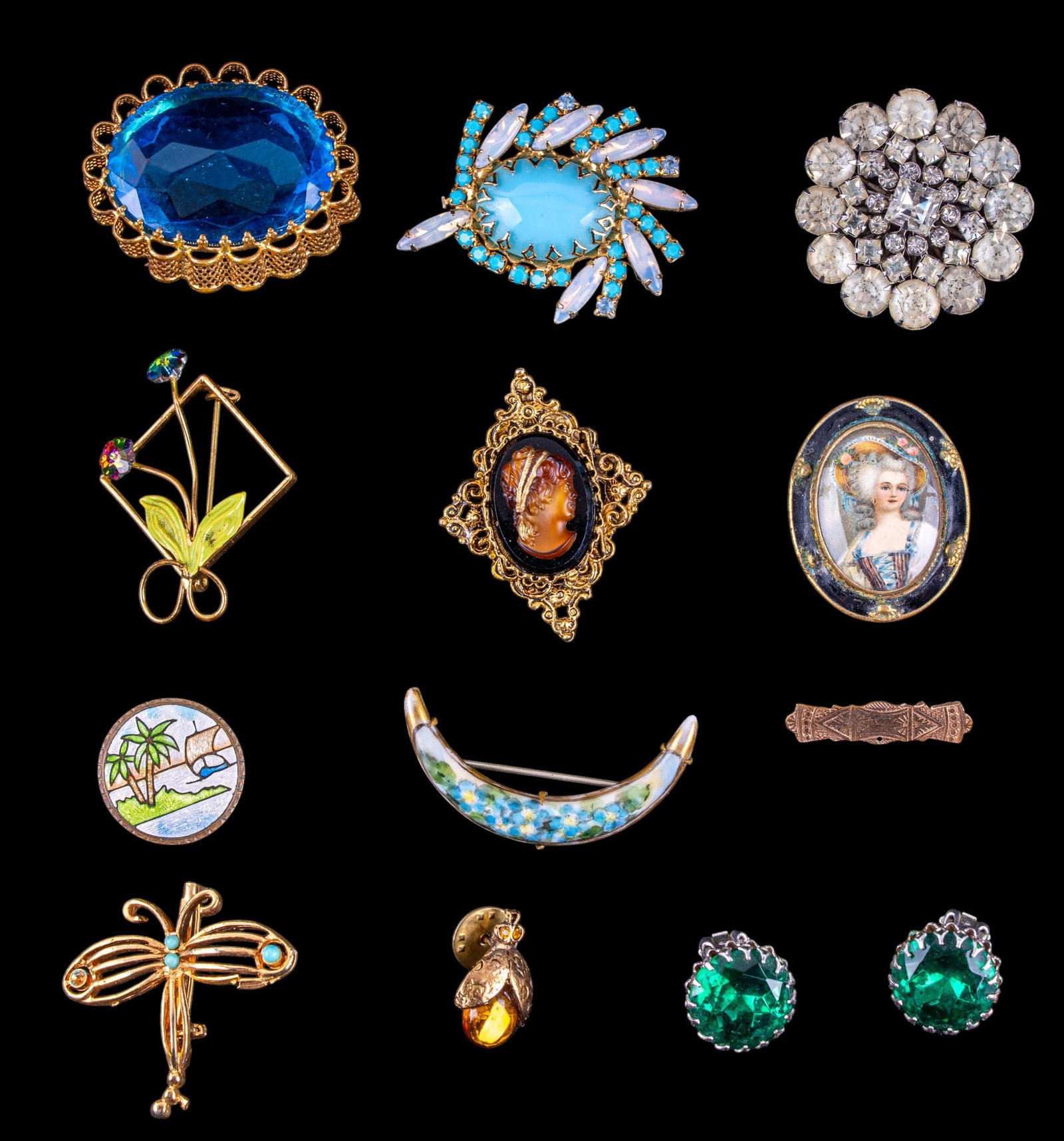 Victorian and Other Brooches: A collection of Victorian and other brooches including a crescent moon painted porcelain brooch, a large blue cut rhinestone brooch with ruffled gold tone edge, a cut crystal and enamel flower brooch