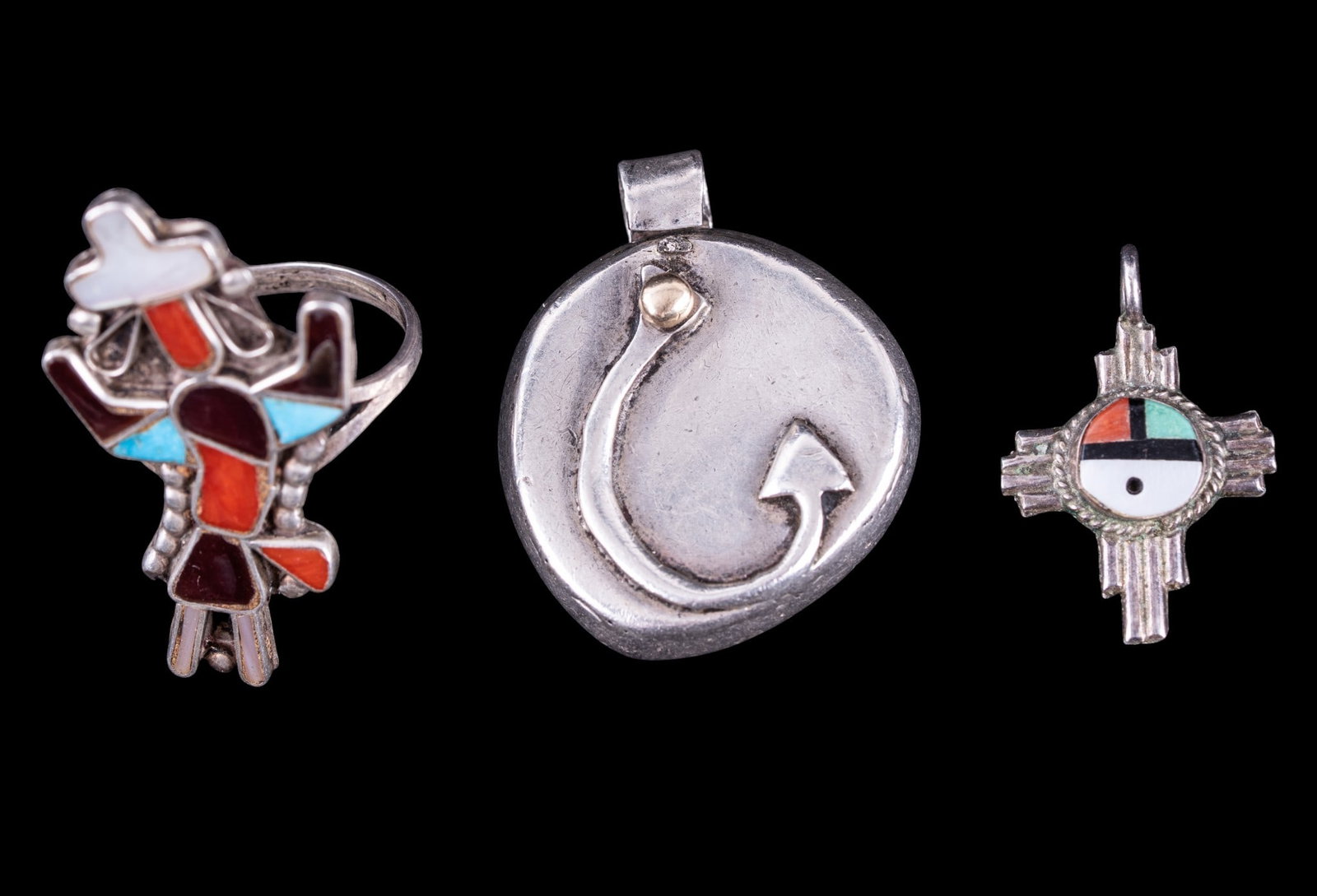 Southwest American Sterling Jewelry: A collection of Southwest American artisan jewelry including a Rainbow man Kachina ring featuring mother of pearl, coral, jasper, and turquoise inlay, signed with a Zuni mark, size 8.5, a fishhook rel