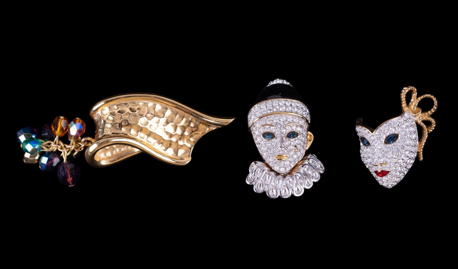 Swarovski and Givenchy Brooches: A set of Swarovski pave crystal and enamel Renaissance style Harlequin mask brooches and a hammered style gold tone ribbon brooch featuring a cluster of iridescent crystal beads by Givenchy.