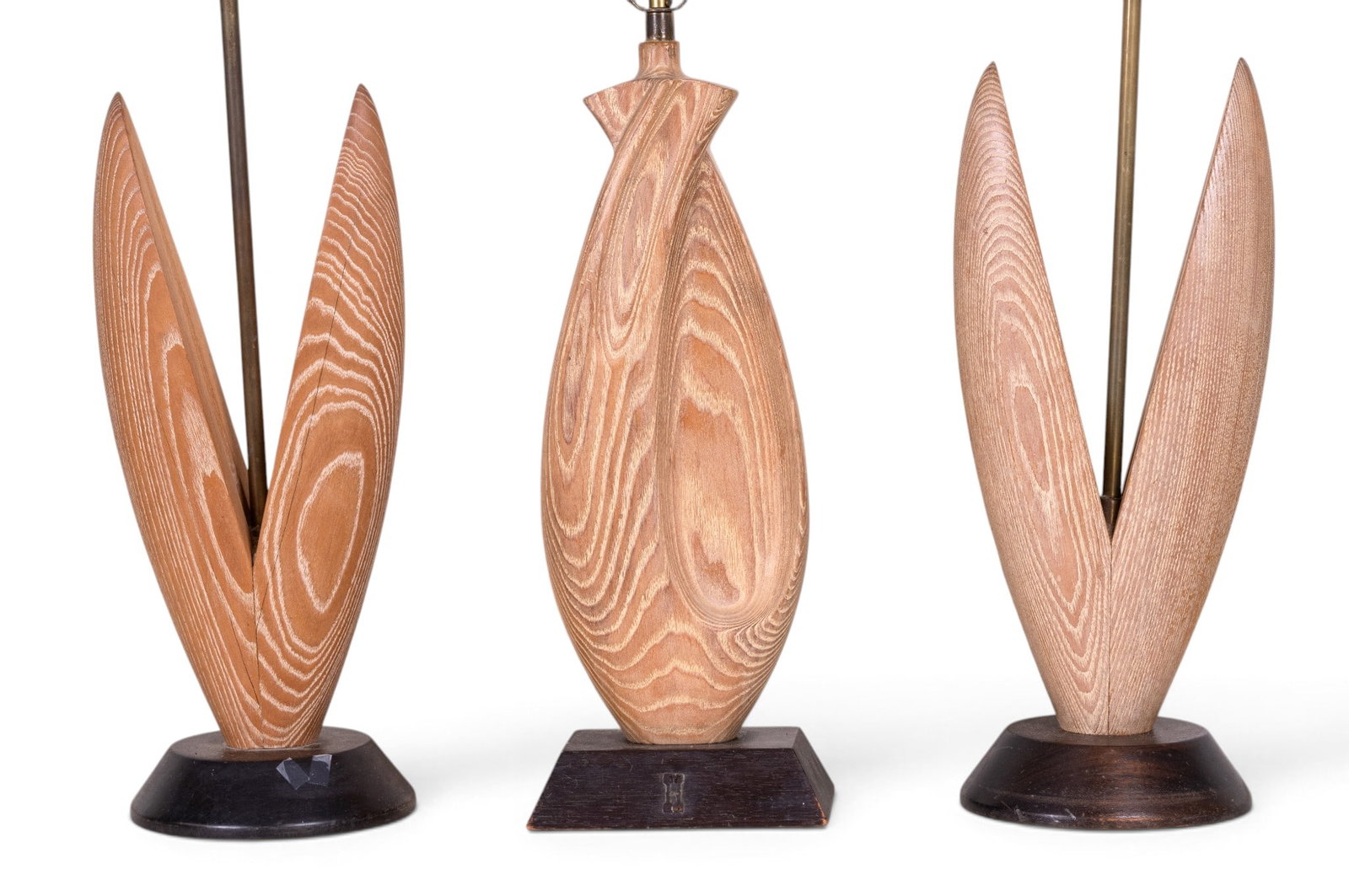 Three MCM Sculptural Wooden Table Lamps: Group of three Mid-Century Modern wooden table lamps, comprising a matching pair with sculptural petal-form wooden bodies on circular bases and a third lamp with an elongated carved wood body on a squ