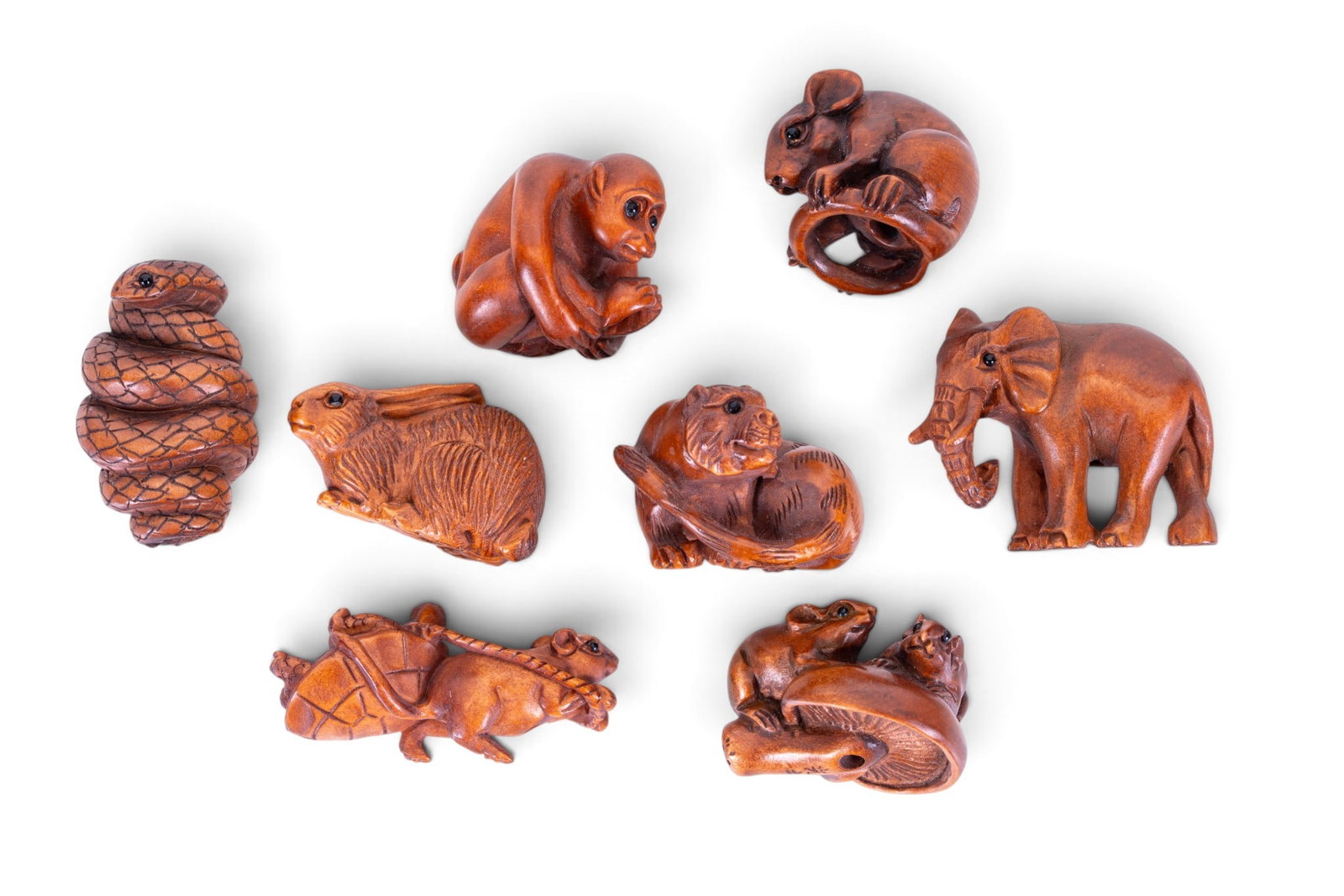Eight Carved Wooden Netsuke: Collection of eight carved wooden netsuke depicting various figures and animals including a monkey, a snake, mice, a mouse pulling a tortoise, an elephant, and more. All examples signed to underside.