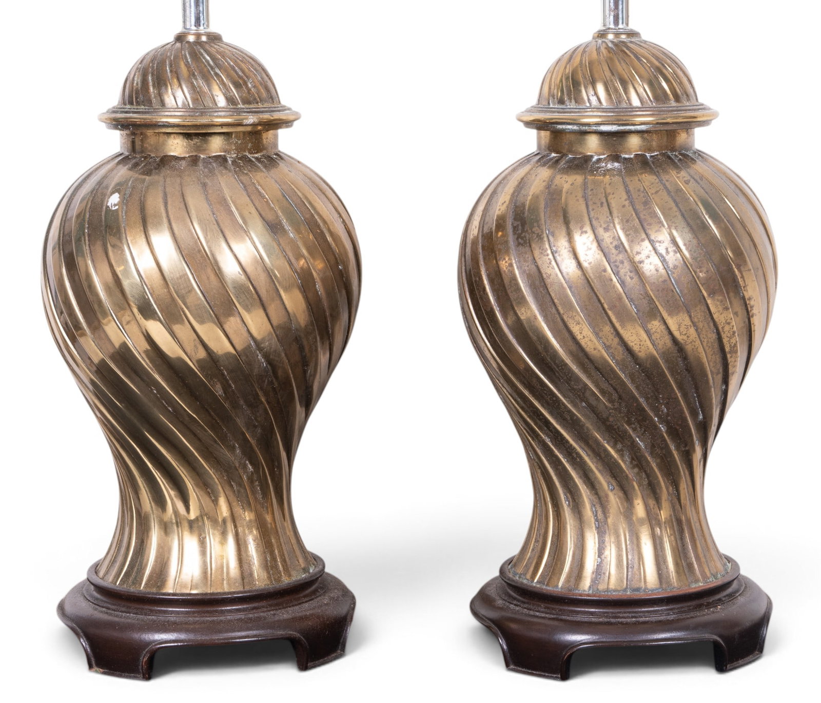 MCM Brass Lamp Pair: A pair of vintage mid century modern brass table lamps on wooden bases featuring a raised swirling motif, both measure approx. 22" H to the socket.