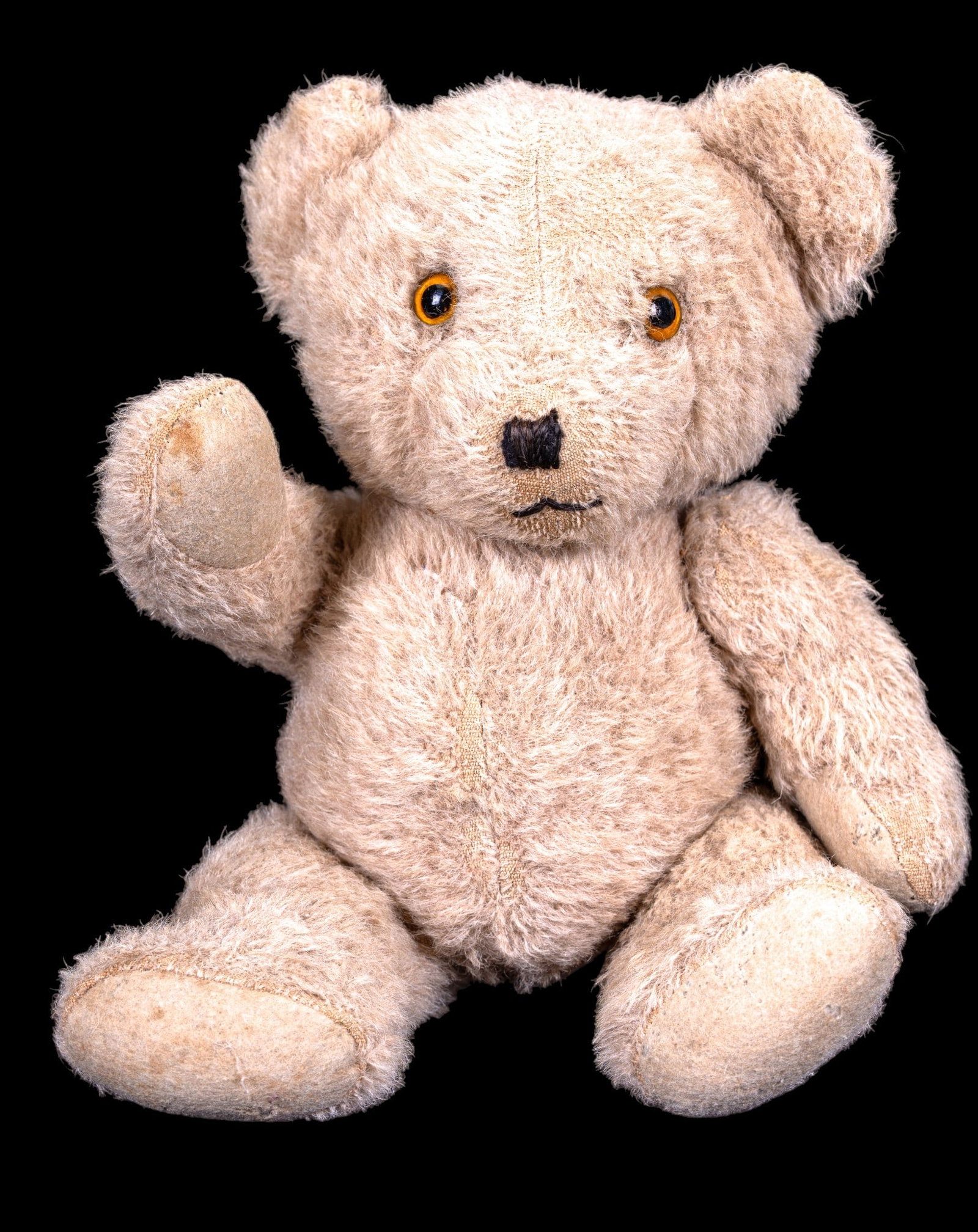 Early Jointed Teddy Bear w/ Amber Glass Eyes: Early teddy bear in a cream-colored plush fur. Traditional amber-colored glass eyed bear, stitched black nose and mouth. Posable bear is fully jointed, allowing for movement of the limbs. Believed to 