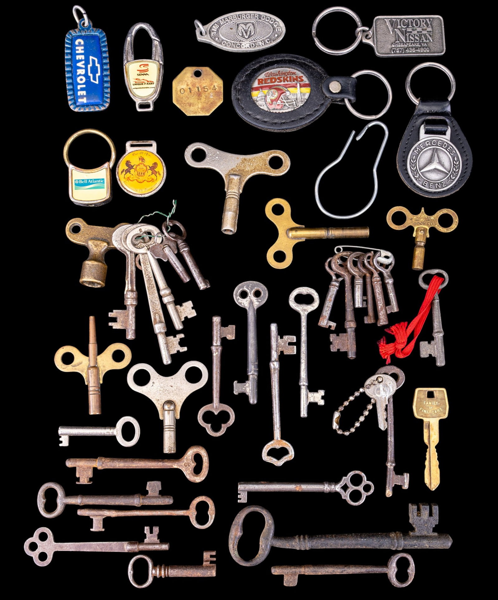 Iron Skeleton Keys, Clock Keys, and More: An assortment of antique iron skeleton keys, brass and other clock keys, and keychains including a vintage Washington Redskins leather wrapped enamel inlay keychain.