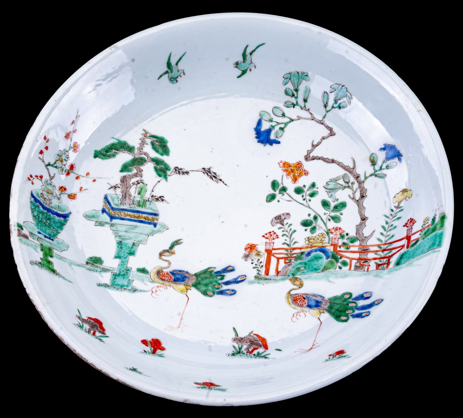 18C Chinese Famille Verte Porcelain Charger: 18th century Chinese porcelain charger decorated in the famille verte palette with a garden scene featuring a pair of peacocks among flowering plants, rockwork, with birds in flight above. The reverse
