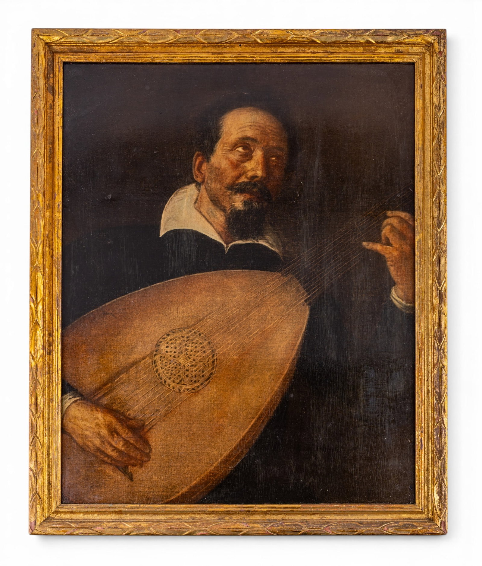Oil on Board of Man Playing Lute: Framed oil on board painting of a man playing a lute. Gold painted wooden frame with some minor scratches. Oil showing a couple of small cracks. Approx. 25 1/2" height x 21" length.