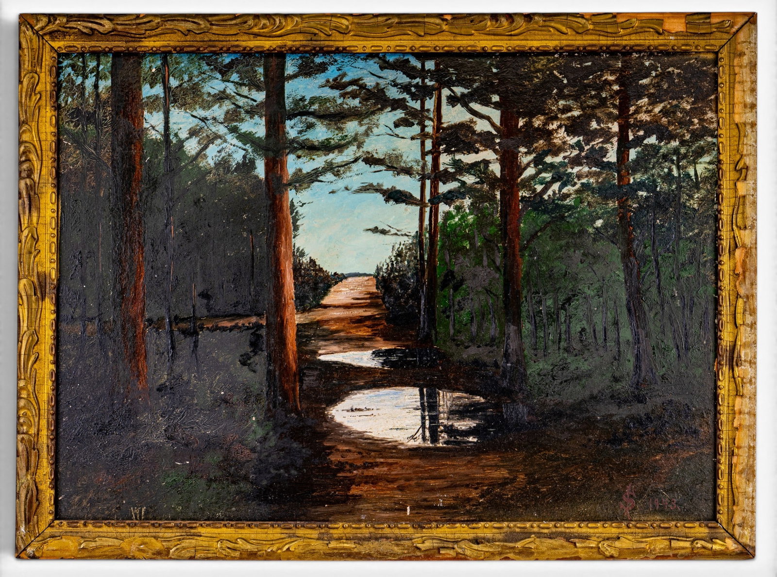 Signed Oil on Board 1943 of a Woodland Scene: Signed and framed oil on board from 1943 featuring a wooded path with some puddles. The wooden frame and painting both show some wear and damage (please see photographs). Approx. 22 1/" x 30 1/4"