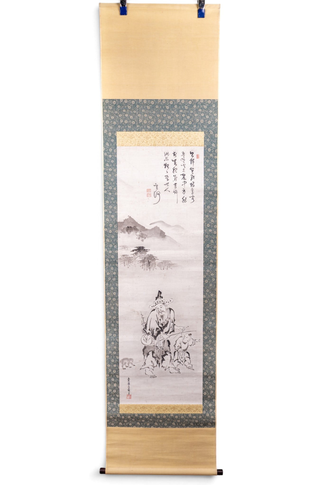 Chinese Ink & Wash Hanging Scroll: Chinese literati Ink and Wash hanging scroll using featuring various concentrations of black ink on paper and framed by a decorative silk brocade featuring a man, child and monkey below a mountain. A