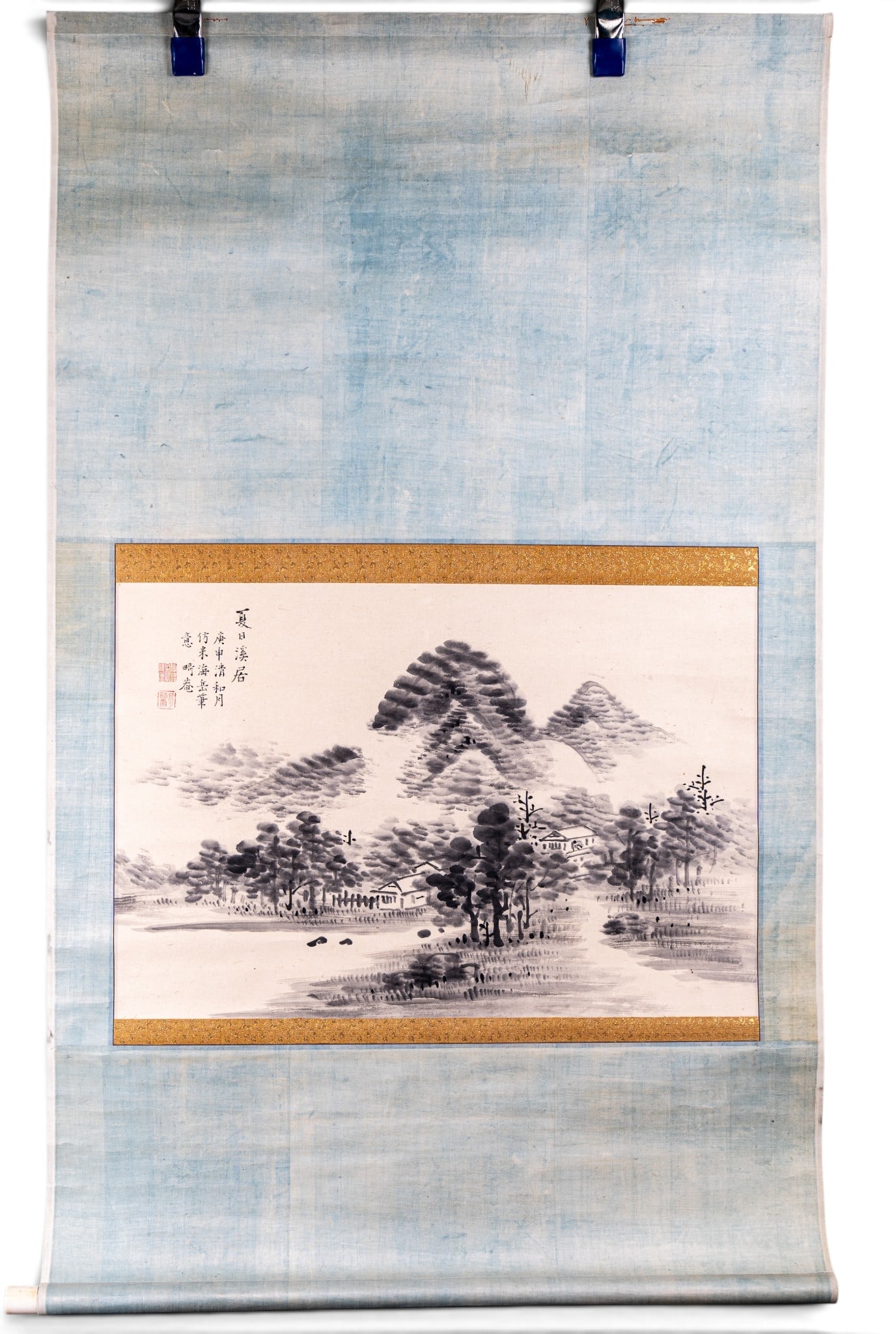 Chinese Scroll in Ink & Wash, Gold Thread Border: Chinese Literati ink and wash scroll on paper featuring mountains and mist, trees, and two houses along with Chinese characters and red chomps, bordered by blue and gold silk. A thin wooden semicircul