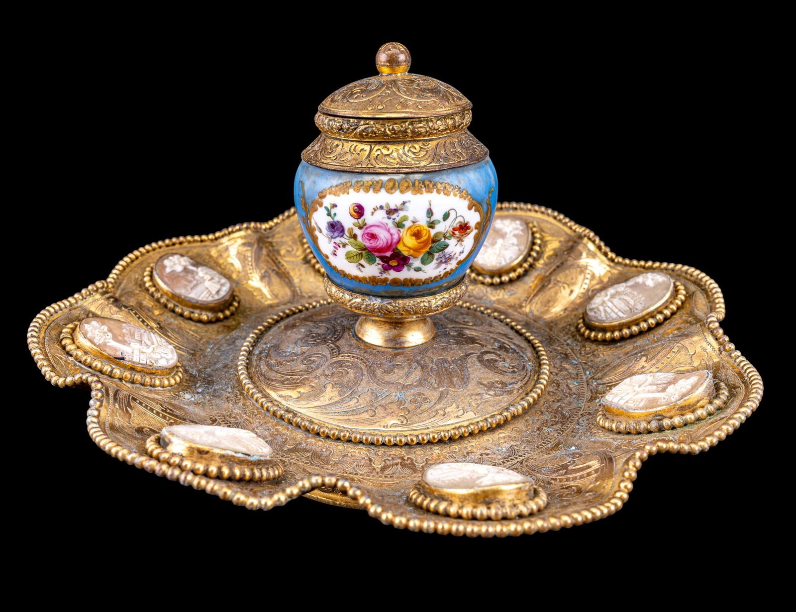 19th C Austrian Hand Painted Bronze Inkwell: A 19th C Austrian bronze inkwell with a hand painted porcelain inkwell on an etched bronze dish featuring eight carved scenic cameos and bead trim. Measures approx. 9" diam x 4.5" H to the finial on t