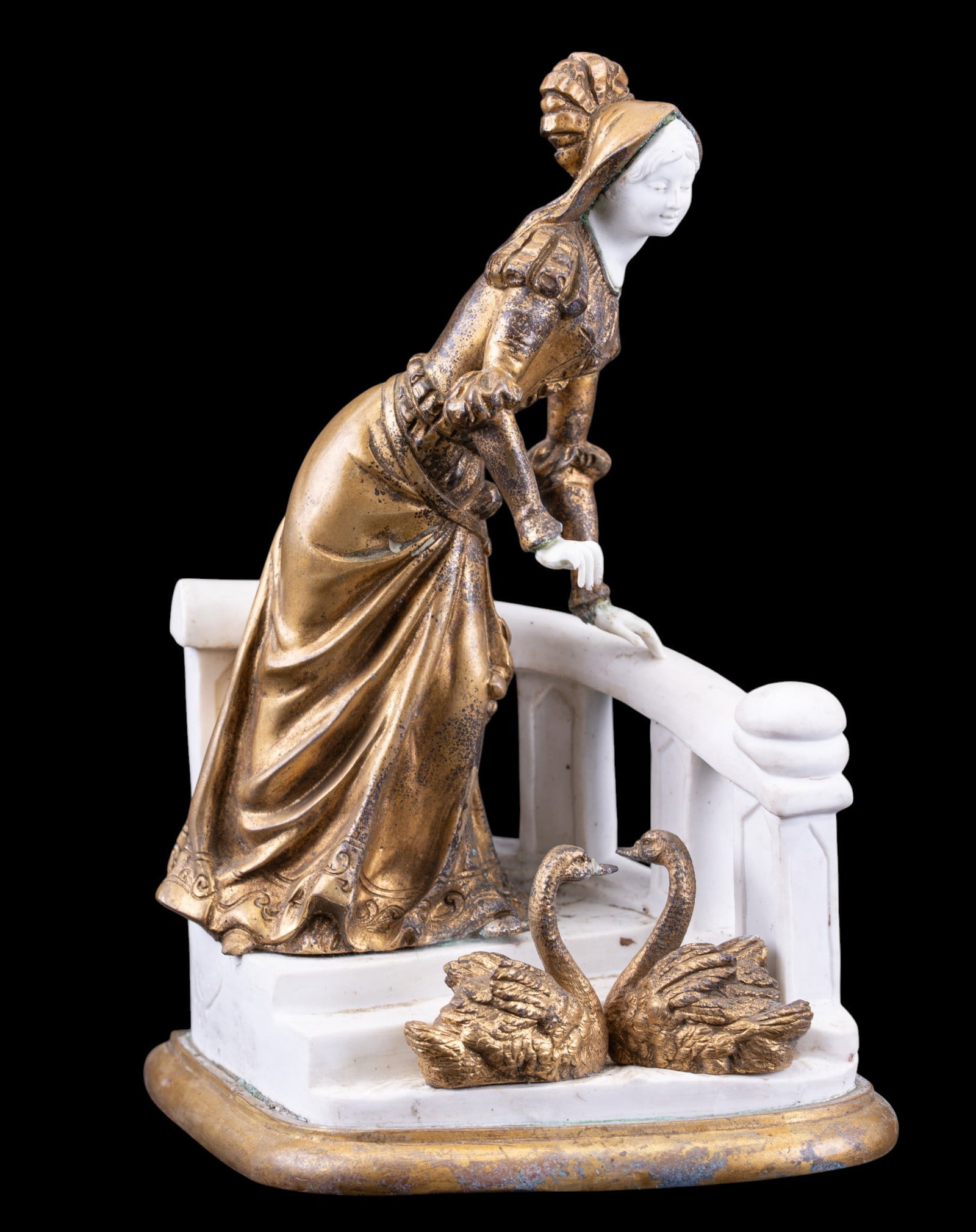 Antique French Bronze & Bisque Porcelain Statuette: An antique French bronze and white bisque porcelain statue depicting a young lady in a dress with a pair of swans, measures approx. 8" W x 5" D x 9.5" H. Note restoration to left hand.
