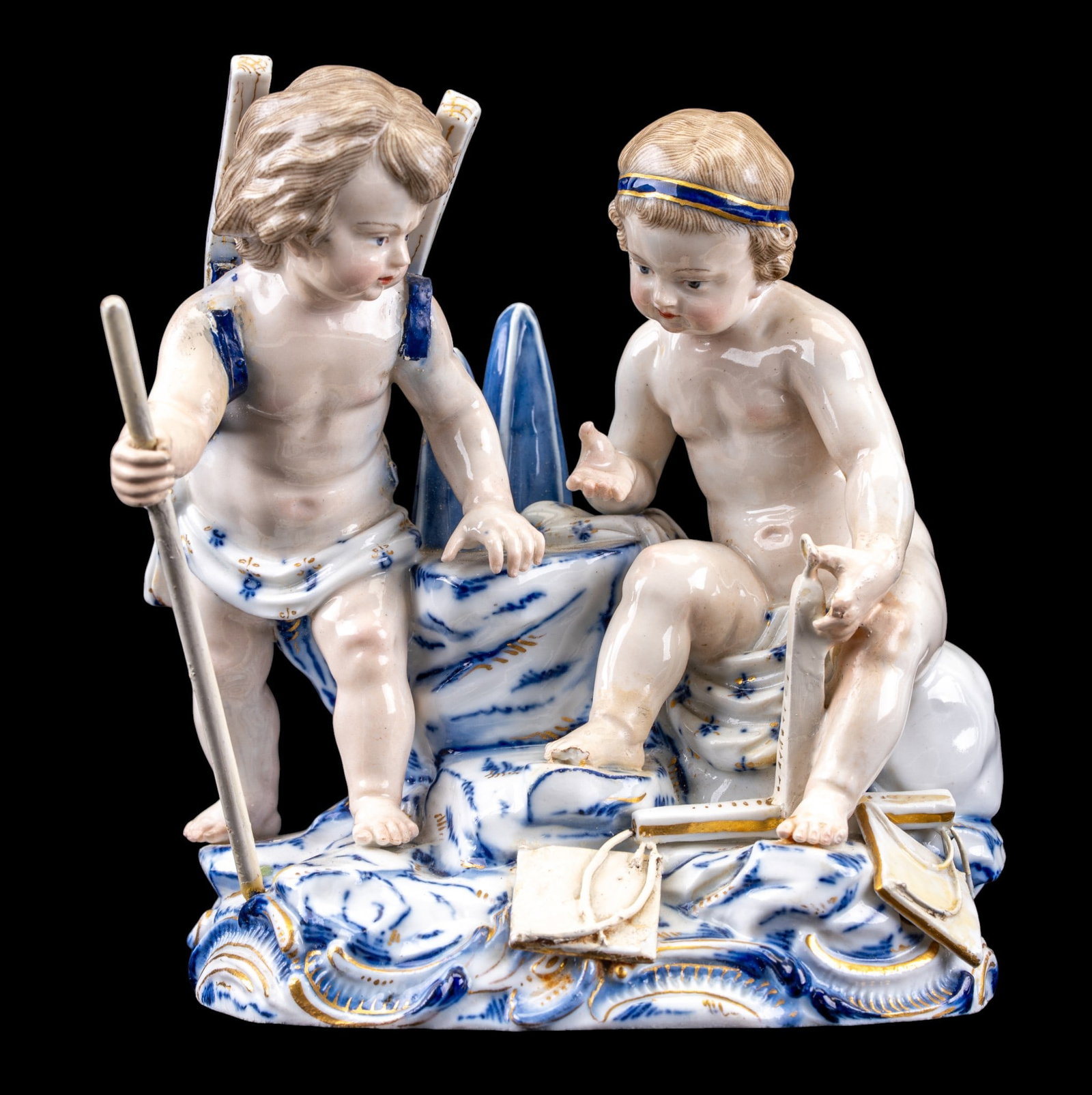 Meissen Porcelain Statuette: A Meissen porcelain statuette depicting two blue, white, and gold decorated children, note some loss as seen in photos, measures approx. 5" W x 5.5" H.