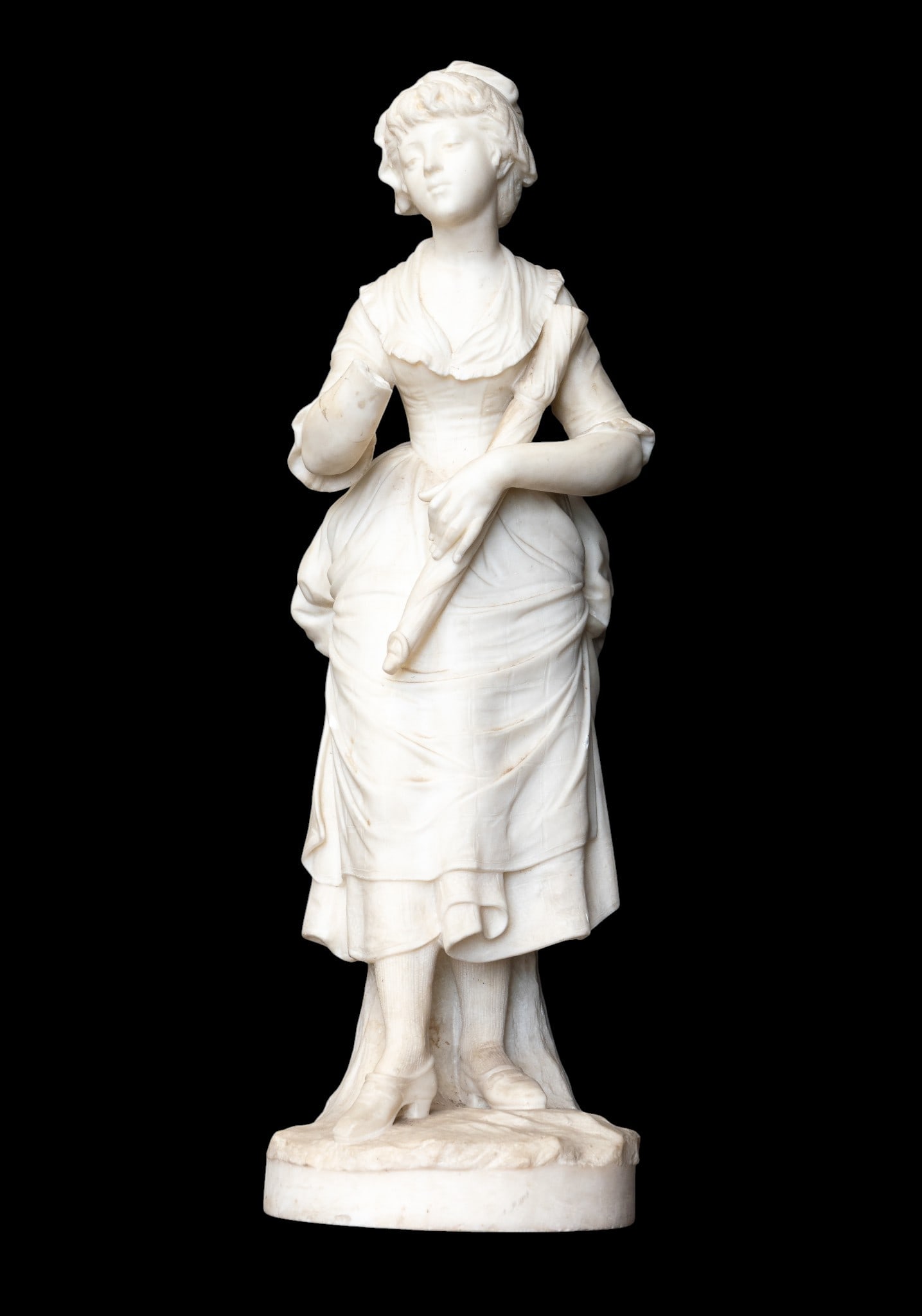 Carved Marble Statue of French Woman: A hand carved solid marble statue of a young French woman / flower girl wearing an apron pulled into a bustle - notice the draping. She has a lace edged shirt, and textured socks. She is holding a par