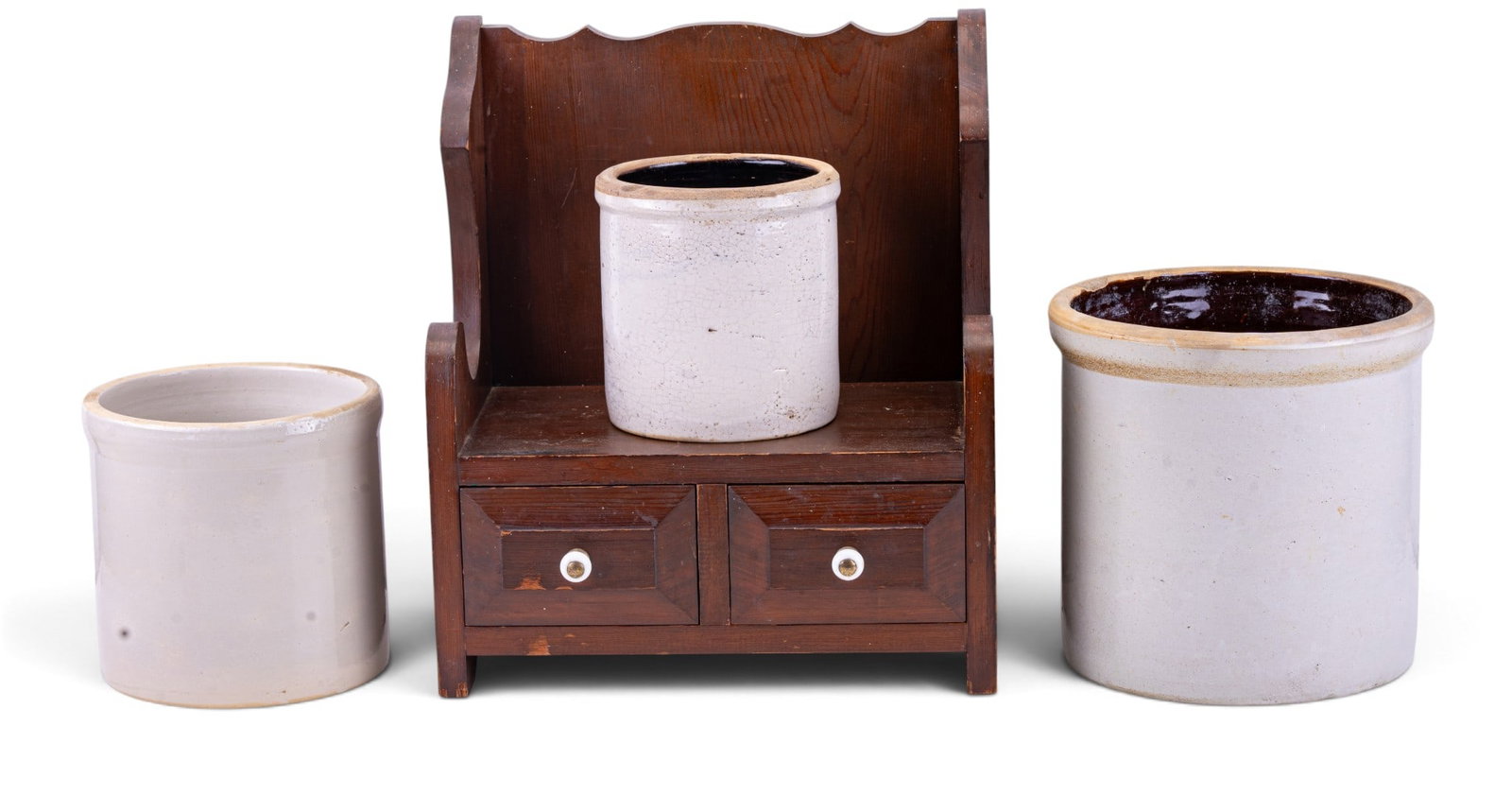 Wooden Two-Drawer Shelf & 3 Stoneware Crocks: Three stoneware pottery crocks in varying sizes with glazed interiors, showing wear and age-related crackling, and a small wooden two-drawer shelf with decorative sides and white knob pulls. The