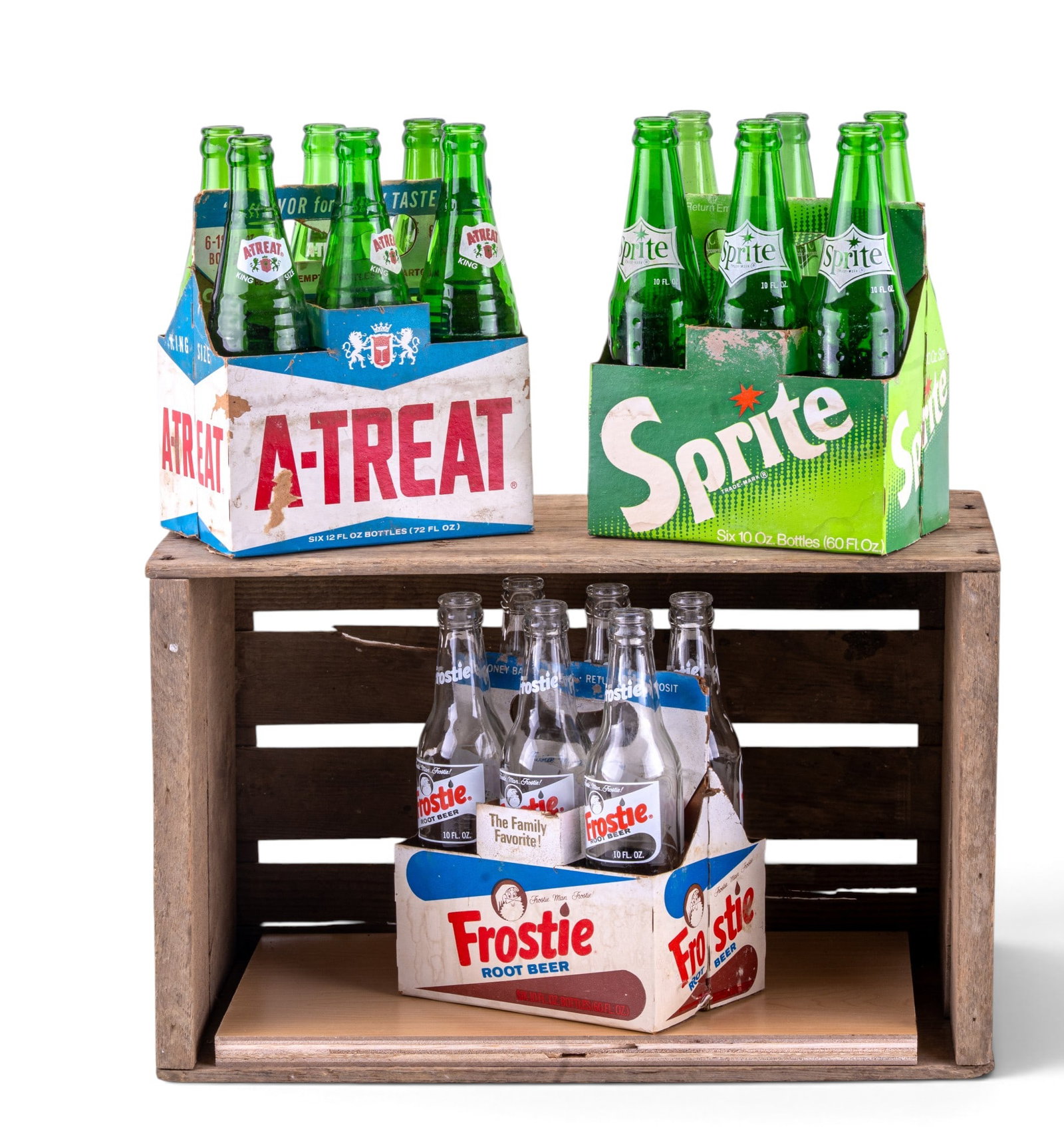 Wooden Crate with Assorted Soda Bottles: Wooden crate containing a variety of empty glass soda bottles. Brands present in the crate include Sprite, Frostie, and Atreat. The bottles are stored in cardboard carriers within the crate, suitable 