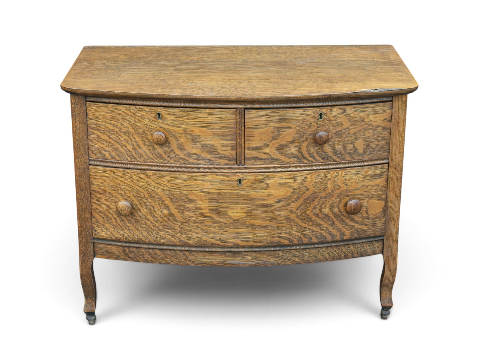 Victorian Tiger Oak Serpentine Dresser: A Victorian Tiger oak serpentine front dresser featuring wooden casters and dovetail joinery, note some veneer loss to right surface edge, no mirror. Measures approx. 36.5" W x 20.5" D x 27.5" H.