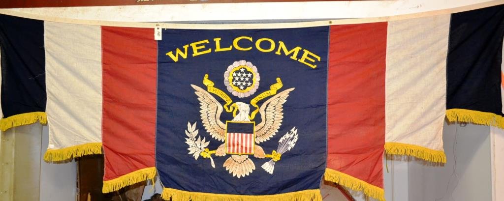 Patriotic Welcome Banner: Patriotic welcome banner from the 1st half of the 20thC, in red, white and blue, trimmed in gold, featuring the American Eagle displayed with olive branches and arrows, E Pluribus Unim, reads "Welcome