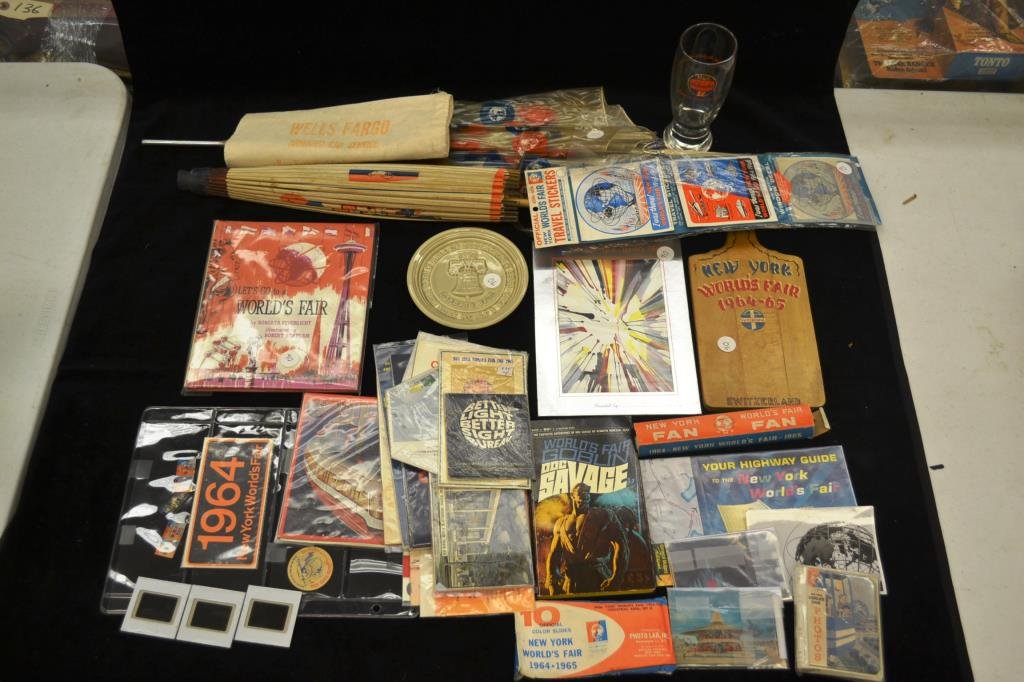 1963 New York Worlds Fair Grouping: Two umbrellas (condition issues) and misc souvenirs including photo albums, a puzzle, advertising, a fan, a cutting board, stickers, a napkin (unused) Wells Fargo bag, and "The Doc Goblin" Worlds Fair